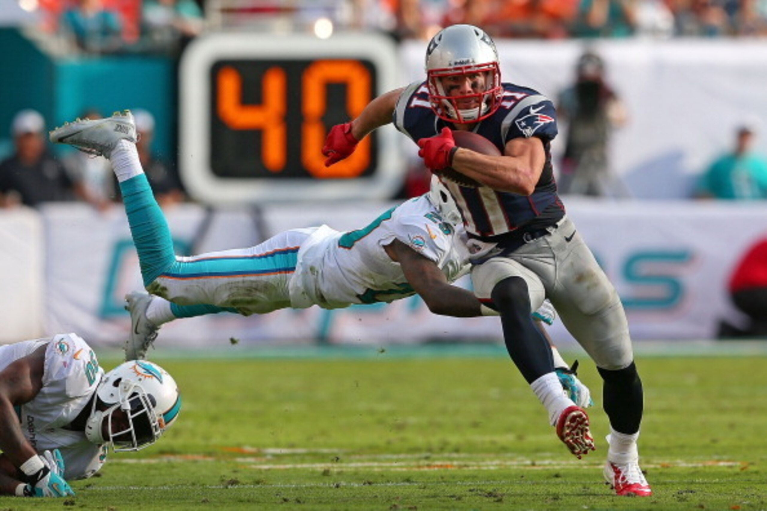 MIAMI GARDENS, FL - DECEMBER 15:  Julian Edelman #11 of the New England Patriots escapes a tackle from Nolan Carroll #28 of the Miami Dolphins during a game  at Sun Life Stadium on December 15, 2013 in Miami Gardens, Florida.  (Photo by Mike Ehrmann/Getty