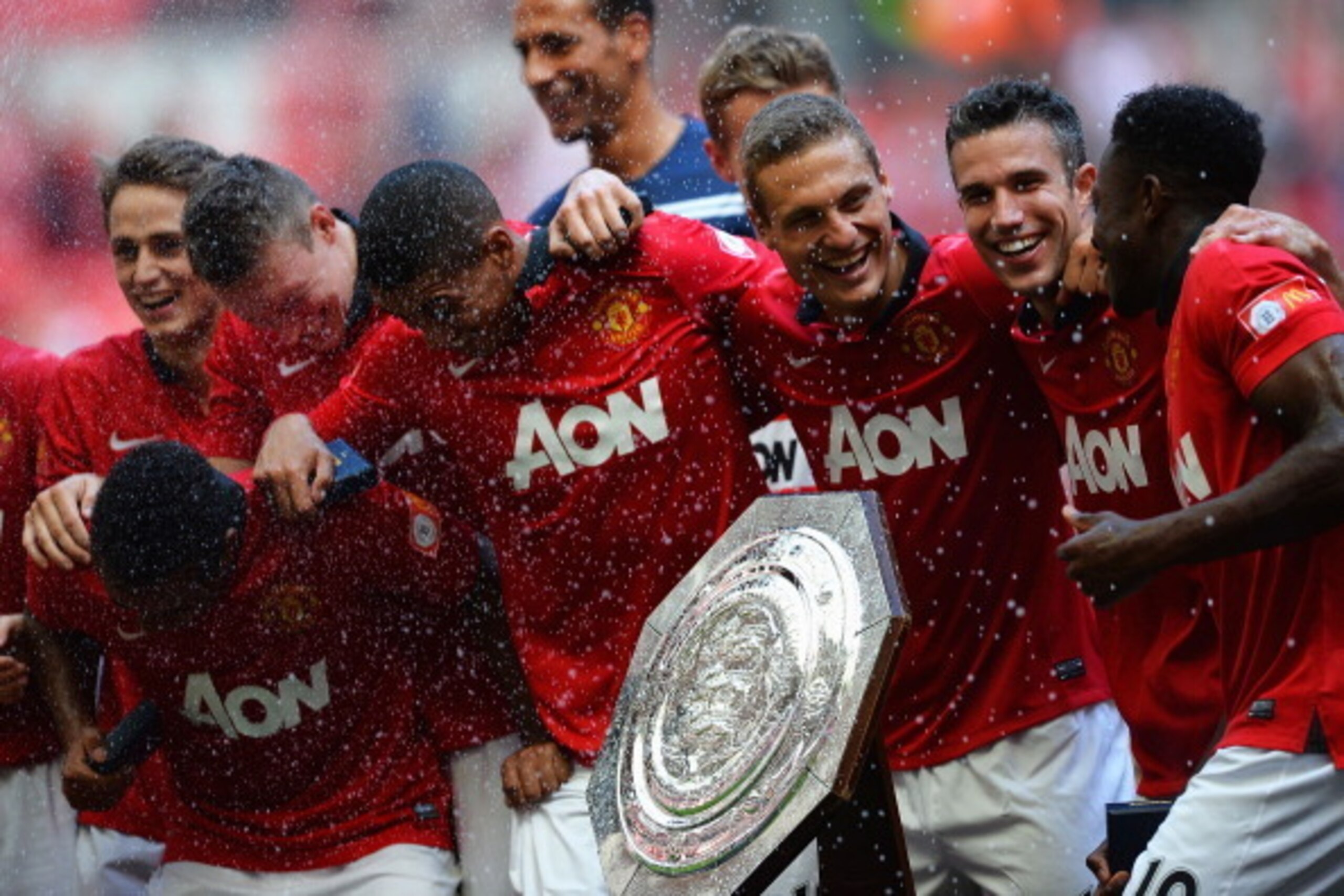 LONDON, ENGLAND - AUGUST 11:  (from right) Danny Welbeck, Robin van Persie and Nemanja Vidic of Manchester United celebrate with the trophy and team mates after victory in the FA Community Shield match between Manchester United and Wigan Athletic at Wembl