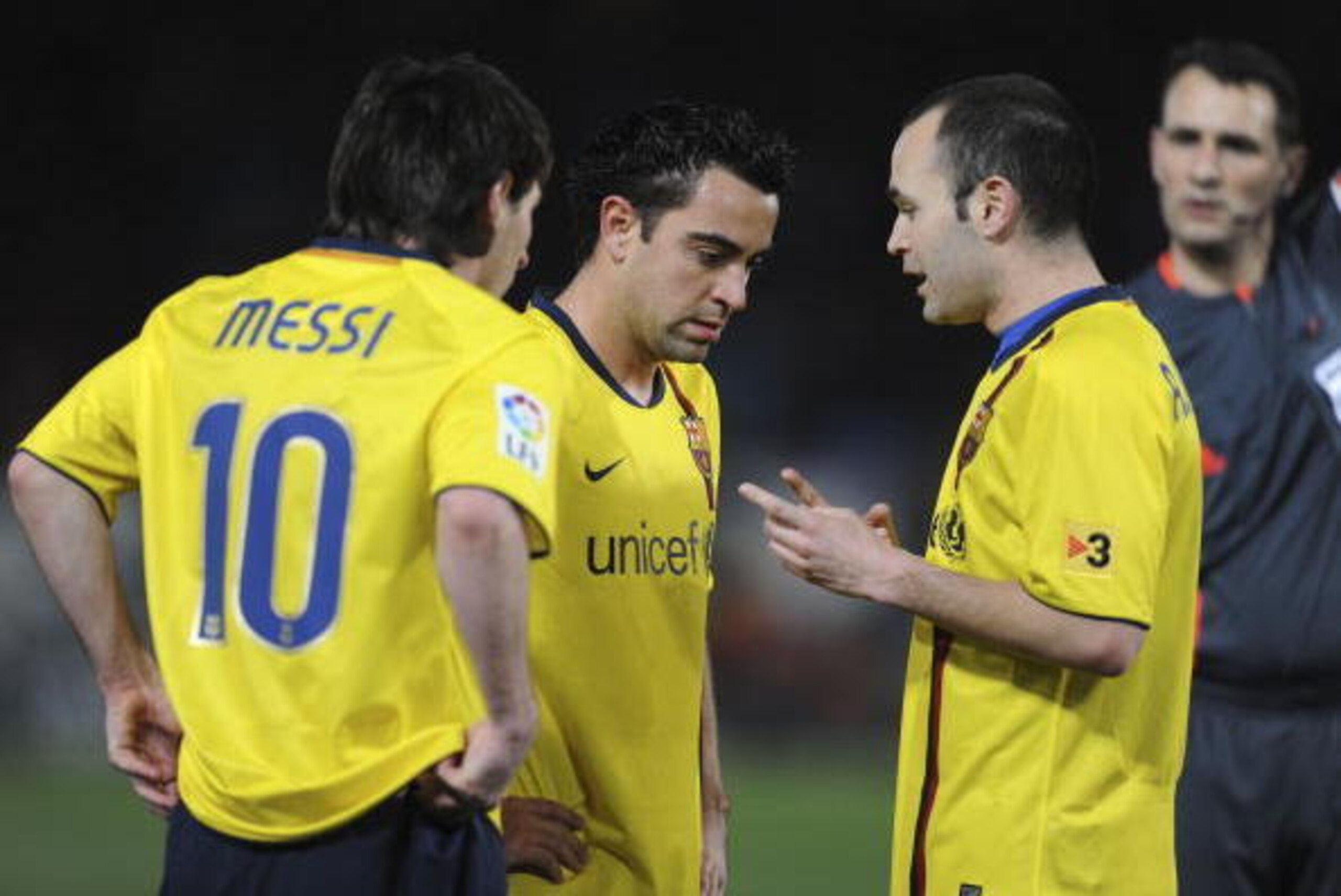ALMERIA, SPAIN - MARCH 06:  Lionel Messi, Xavi Hernandez and Andres Iniesta (R) of Barcelona talk before Messi scored from a free kick during the La Liga match between UD Almeria and Barcelona at Estadio del Mediterraneo on March 6, 2010 in Almeria, Spain