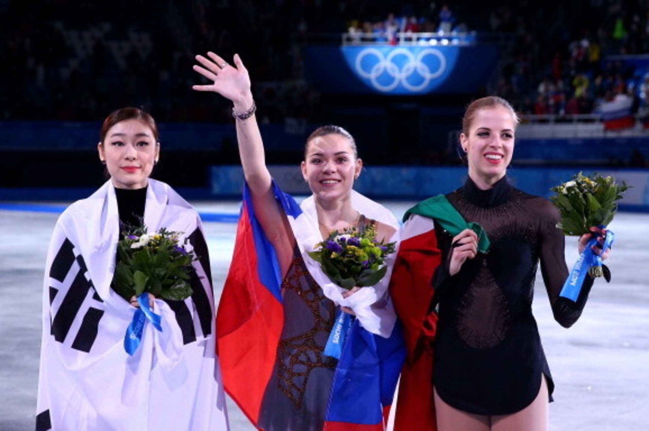 SOCHI, RUSSIA - FEBRUARY 20:  (L-R) Silver medalist Yuna Kim of South Korea, gold medalist Adelina Sotnikova of Russia and bronze medalist Carolina Kostner of Italy celebrate during the flower ceremony for the Ladies' Figure Skating on day 13 of the Sochi