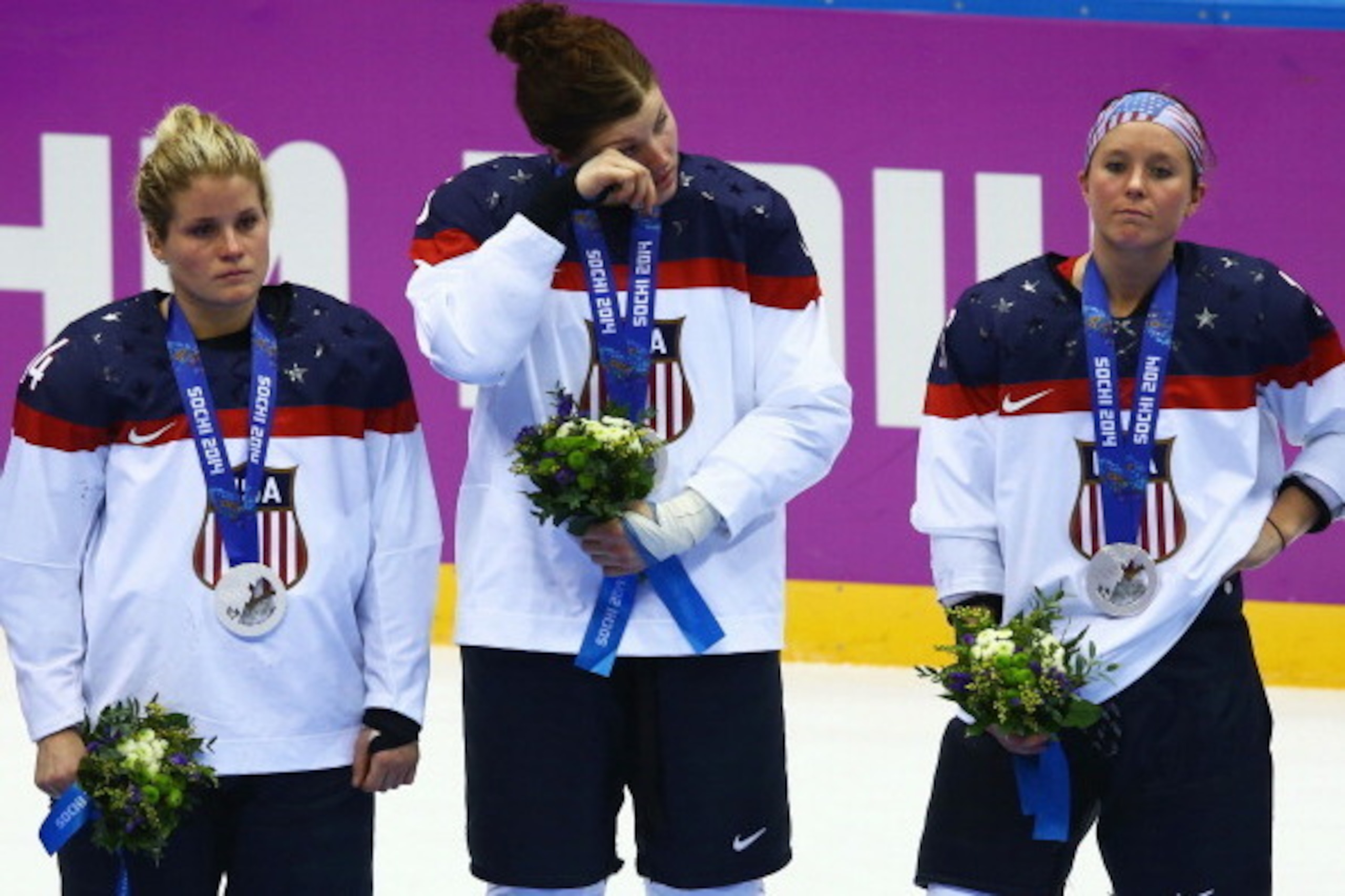 SOCHI, RUSSIA - FEBRUARY 20:  (L-R) Silver medalists Brianna Decker #14, Anne Schleper #15 and Kelli Stack #16 of the United States react during the flower ceremony for the Ice Hockey Women's Gold Medal Game on day 13 of the Sochi 2014 Winter Olympics at 