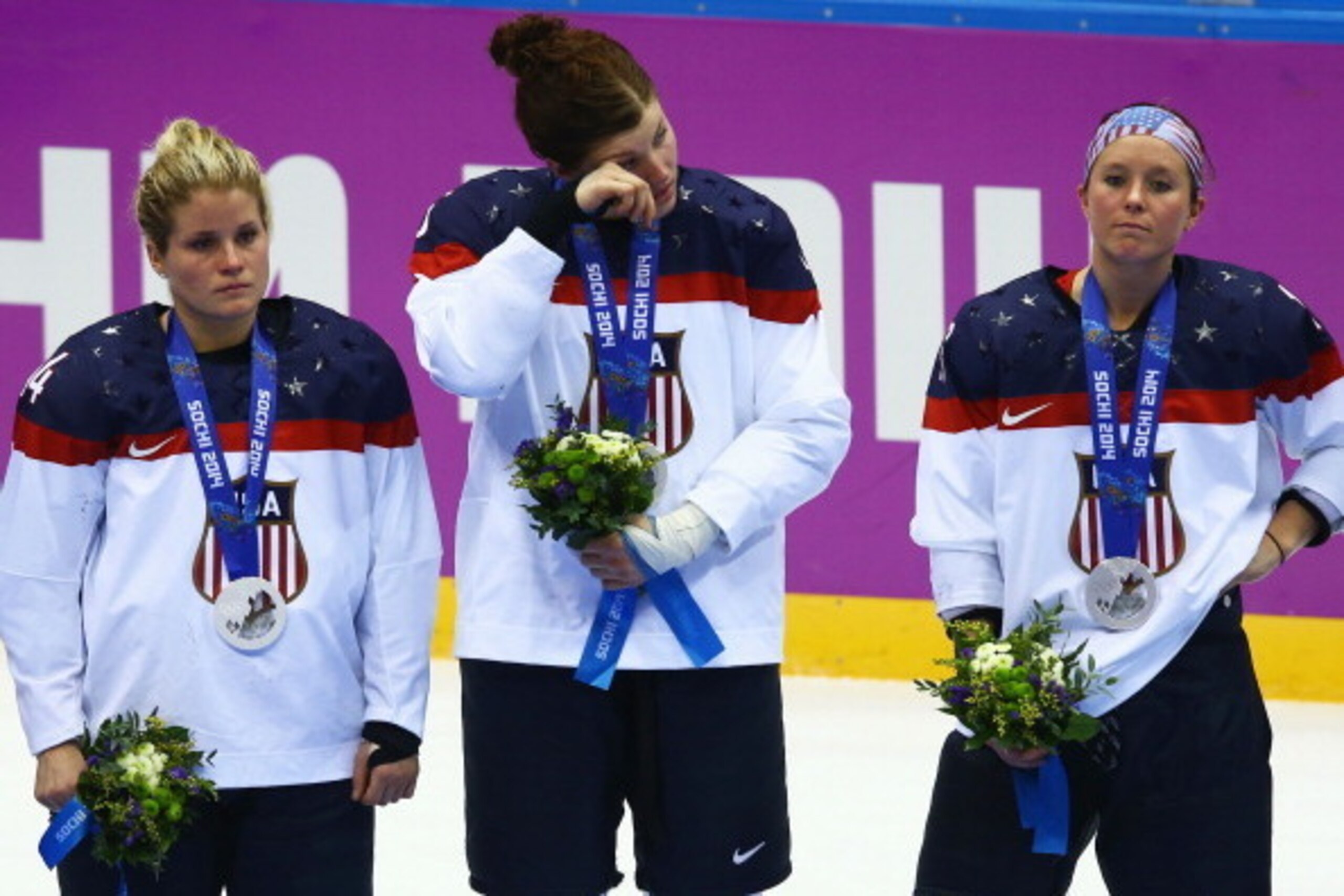 SOCHI, RUSSIA - FEBRUARY 20:  (L-R) Silver medalists Brianna Decker #14, Anne Schleper #15 and Kelli Stack #16 of the United States react during the flower ceremony for the Ice Hockey Women's Gold Medal Game on day 13 of the Sochi 2014 Winter Olympics at 