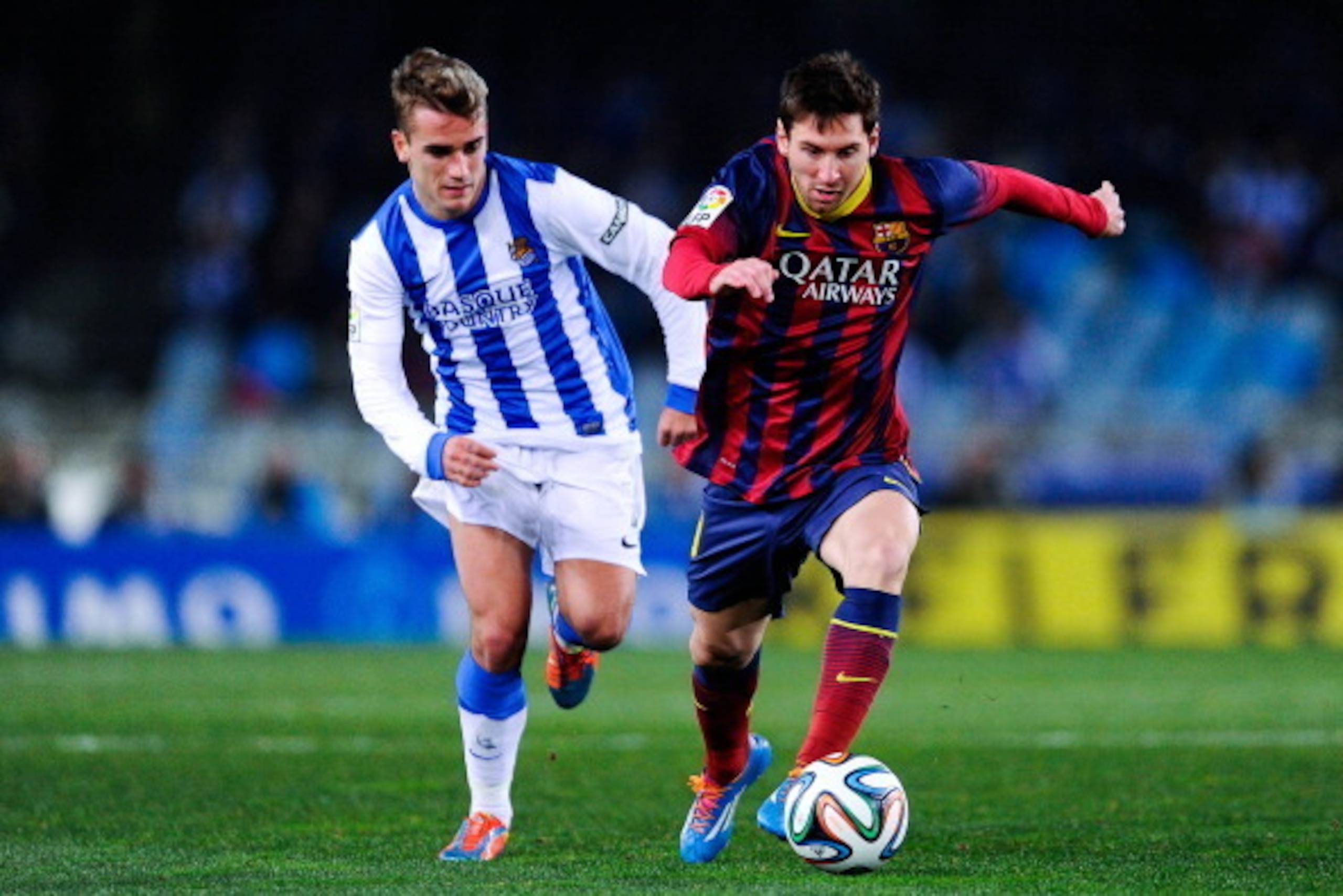 SAN SEBASTIAN, SPAIN - FEBRUARY 12:  Lionel Messi of FC Barcelona runs with the ball chased by Antoine Griezmann of Real Sociedad during the Copa del Rey Semi Final second leg between Real Sociedad and FC Barcelona at Anoeta Stadium on February 12, 2014 i