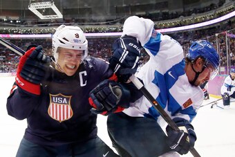 Feb 22, 2014; Sochi, RUSSIA; USA forward Zach Parise (9) battles for the puck along the boards with Finland defenseman Sami Lepisto (18) in the men's ice hockey bronze medal game during the Sochi 2014 Olympic Winter Games at Bolshoy Ice Dome. Mandatory Cr