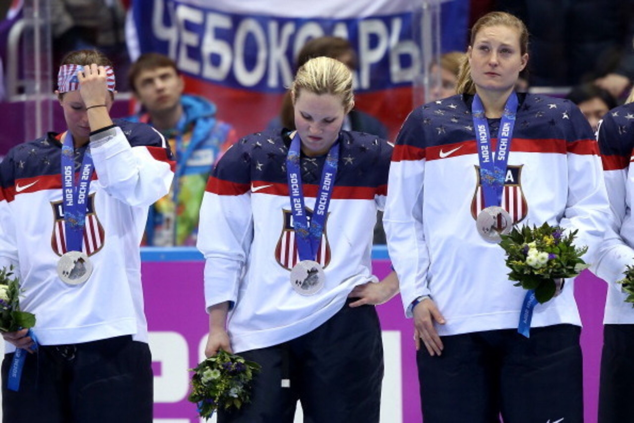 SOCHI, RUSSIA - FEBRUARY 20:  Kelli Stack #16, Jocelyne Lamoureux #17 and Lyndsey Fry #18 of the United States react during the flower ceremony after losing to Canada 3-2 during the Ice Hockey Women's Gold Medal Game on day 13 of the Sochi 2014 Winter Oly