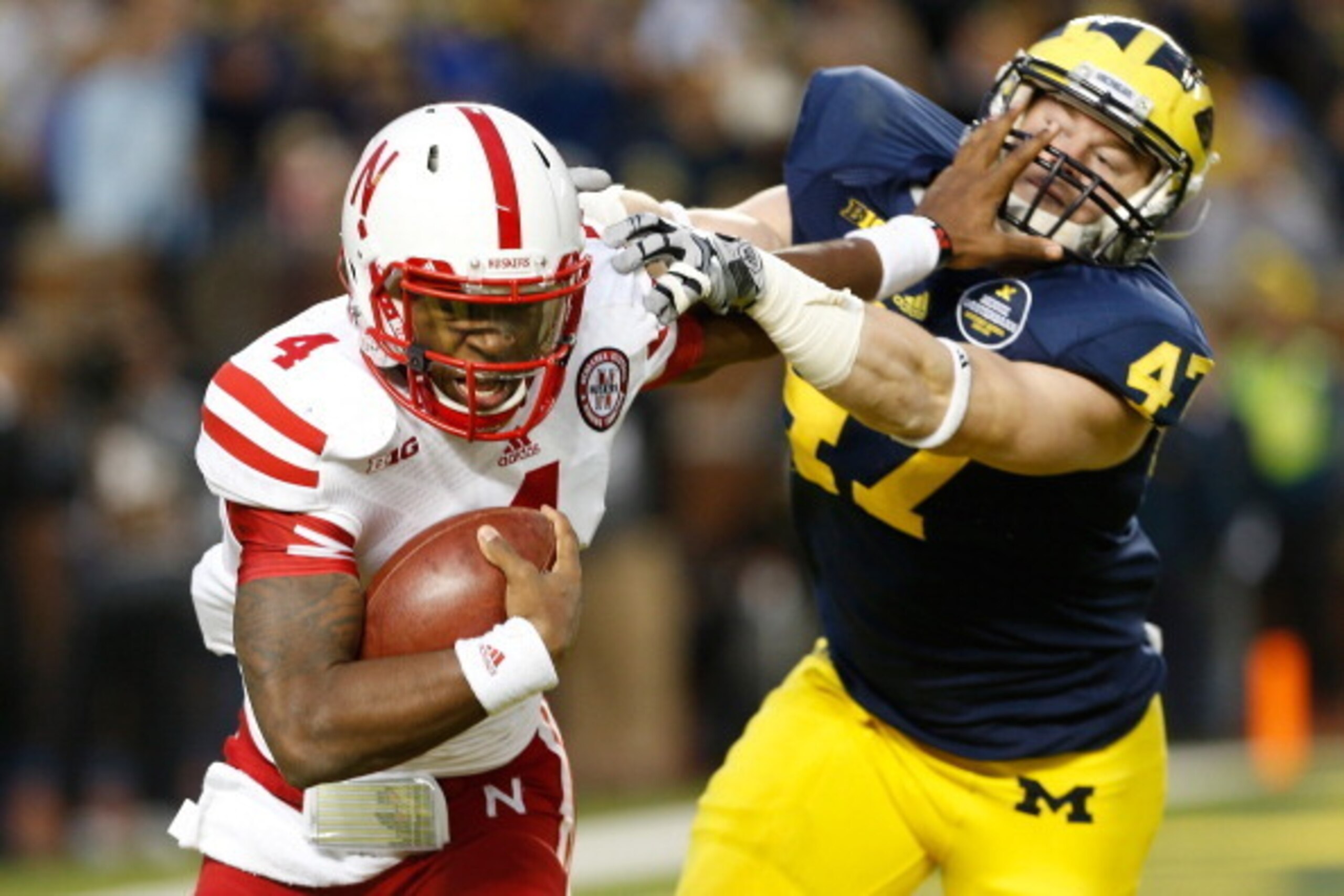 ANN ARBOR, MI - NOVEMBER 09:  Tommy Armstrong Jr. #4 of the Nebraska Cornhuskers stiff arms Jake Ryan #47 of the Michigan Wolverines in the second quarter at Michigan Stadium on November 9, 2013 in Ann Arbor, Michigan.  (Photo by Gregory Shamus/Getty Imag