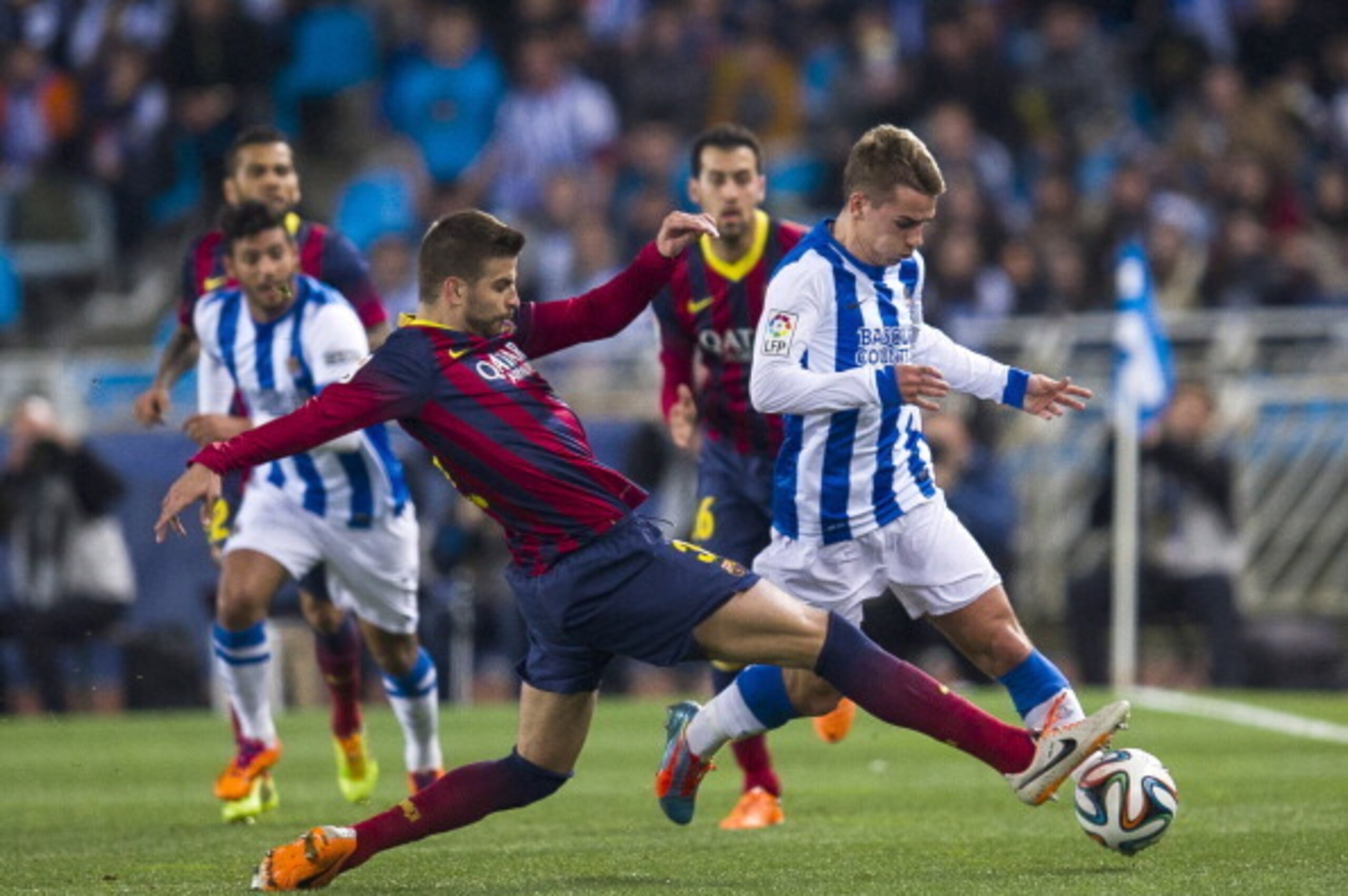 SAN SEBASTIAN, SPAIN - FEBRUARY 12:  Gerard Pique of FC Barcelona duels for the ball with Antoine Griezmann of Real Sociedad during the Copa del Rey Semi-Final first leg match between Real Sociedad and Barcelona at Estadio Anoeta  on February 12, 2014 in 