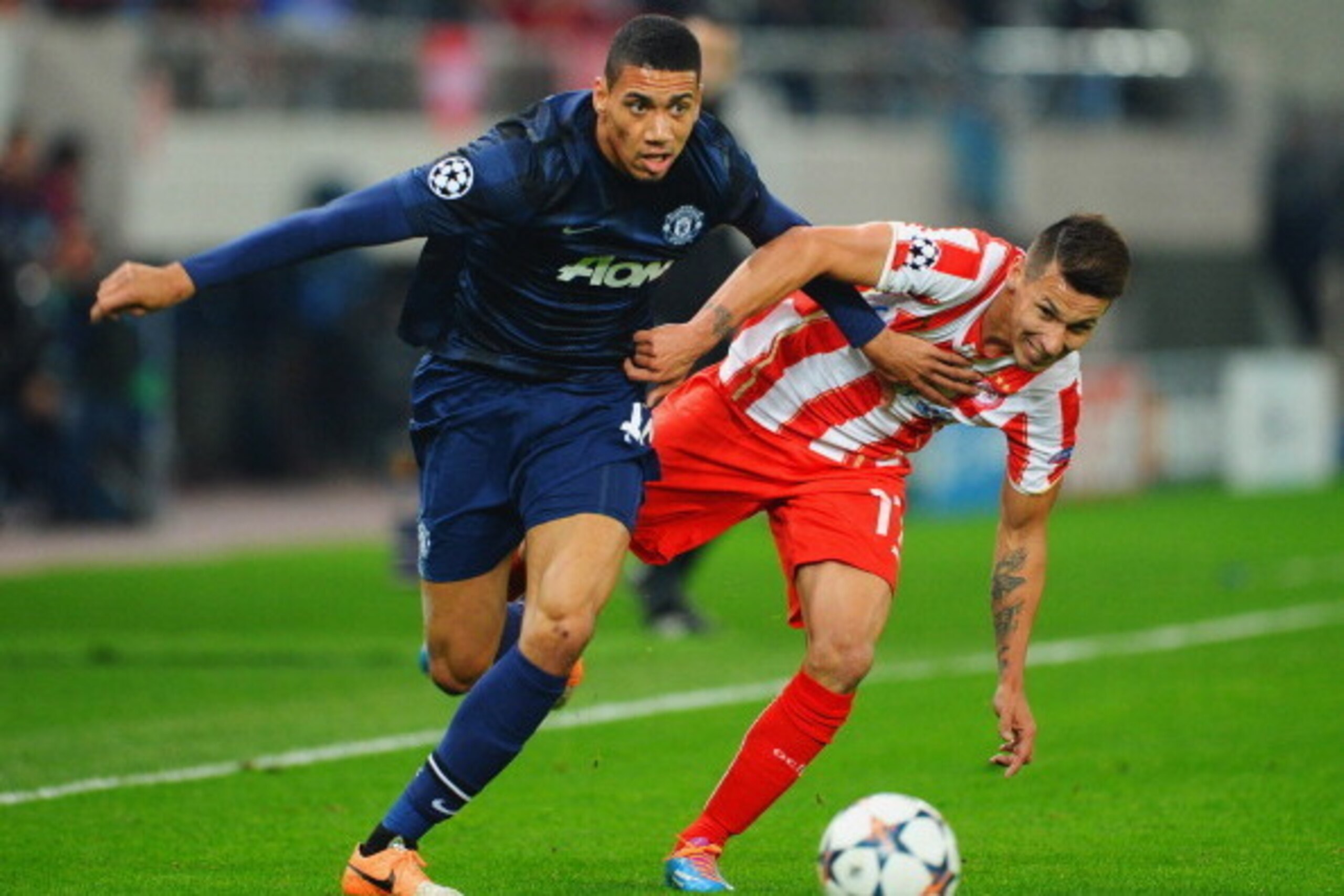 PIRAEUS, GREECE - FEBRUARY 25:  Chris Smalling (L) of Manchester United holds off the challenge of Hernan Perez (R) of Olympiacos during the UEFA Champions League Round of 16 first leg match between Olympiacos FC and Manchester United at Karaiskakis Stadi