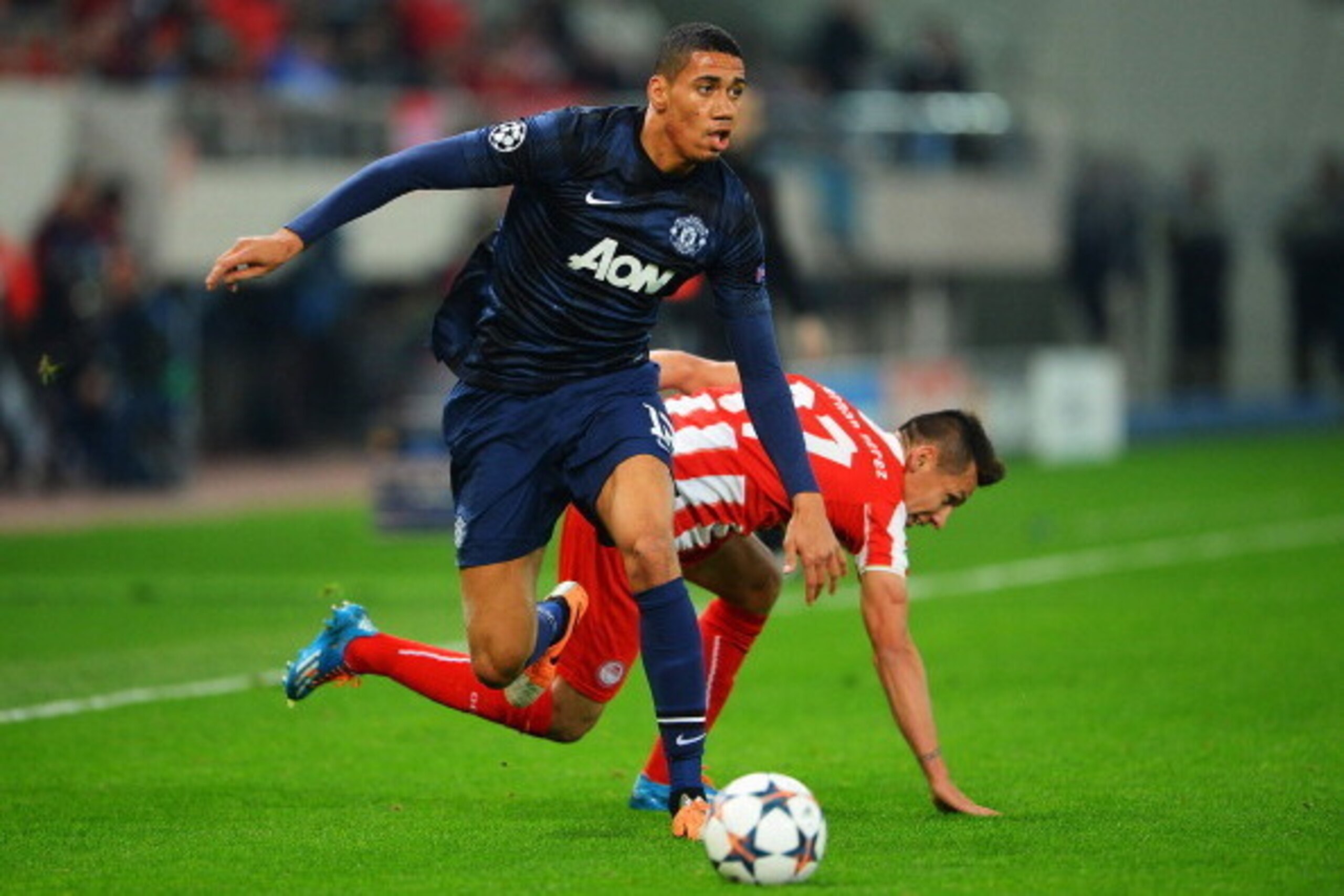 PIRAEUS, GREECE - FEBRUARY 25:  Chris Smalling (L) of Manchester United holds off the challenge of Hernan Perez (R) of Olympiacos during the UEFA Champions League Round of 16 first leg match between Olympiacos FC and Manchester United at Karaiskakis Stadi