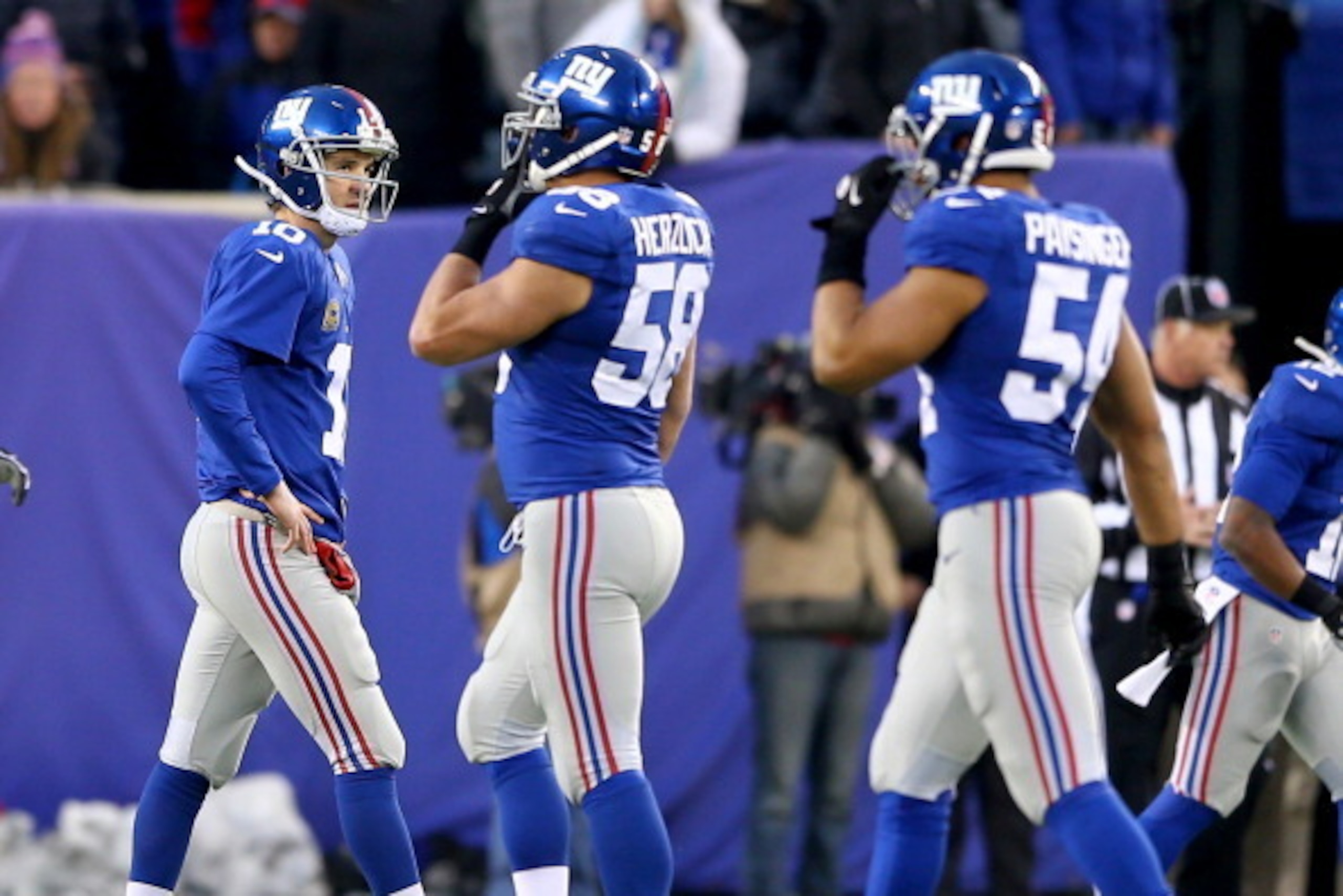 EAST RUTHERFORD, NJ - DECEMBER 15:   Eli Manning #10 of the New York Giants walks off the field after a failed drive as teammates  Mark Herzlich #58 and  Spencer Paysinger #54 walk by in the fourth quarter against the Seattle Seahawks at MetLife Stadium o