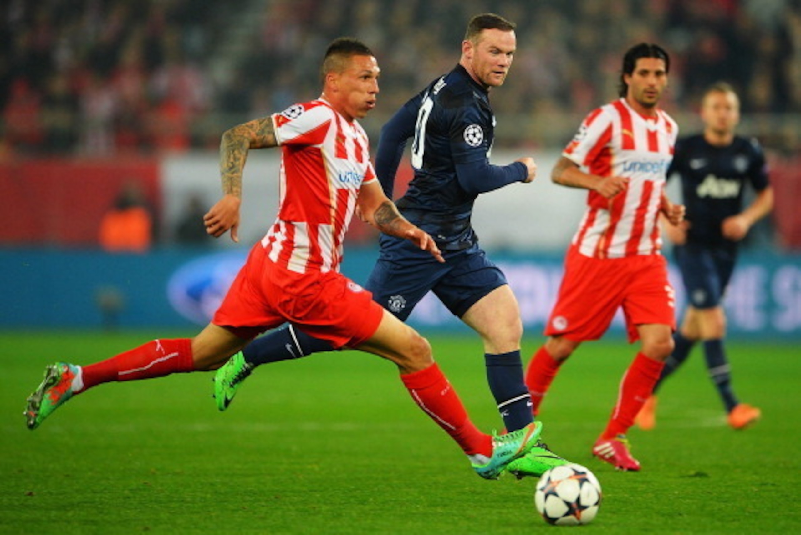 PIRAEUS, GREECE - FEBRUARY 25:  Jose Holebas (L) of Olympiacos holds off the challenge of Wayne Rooney of Manchester United during the UEFA Champions League Round of 16 first leg match between Olympiacos FC and Manchester United at Karaiskakis Stadium on 