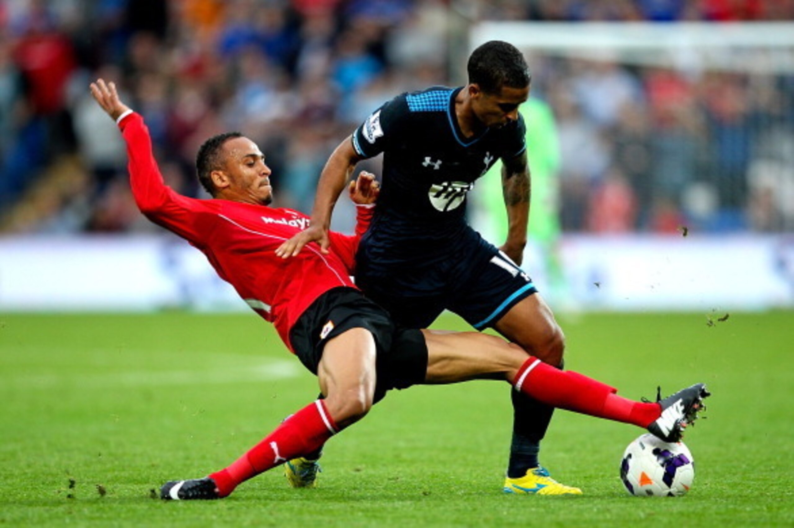 CARDIFF, WALES - SEPTEMBER 22:  Kyle Naughton of Tottenham is tackled by Peter Odemwingie of Cardiff during the Barclays Premier League match between Cardiff City and Tottenham Hotspur at Cardiff City Stadium on September 22, 2013 in Cardiff, Wales.  (Pho