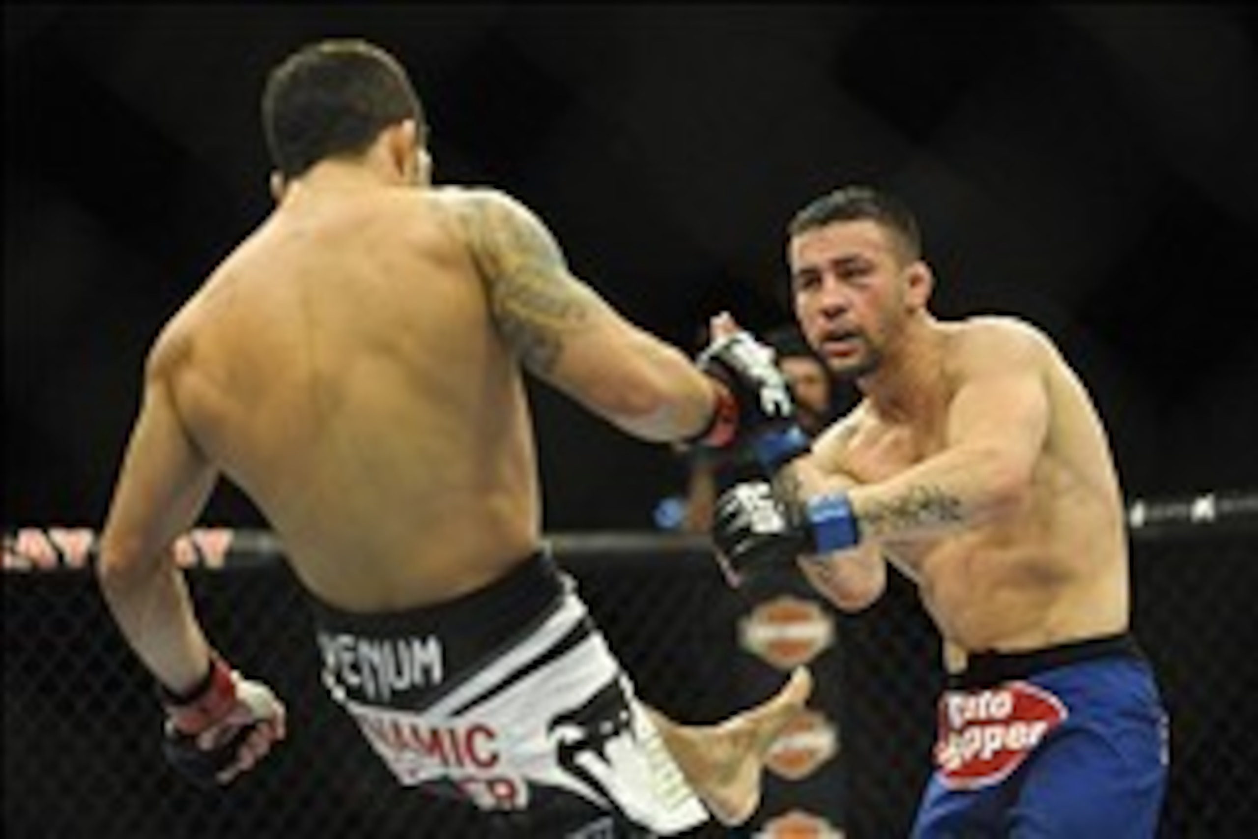 Feb 22, 2014; Las Vegas, NV, USA; Pedro Munhoz (blue gloves) attempts to block a kick from Raphael Assuncao (red gloves) during their UFC bantamweight bout at Mandalay Bay. Assuncao won by unanimous decision 30-27.  Mandatory Credit: Stephen R. Sylvanie-U