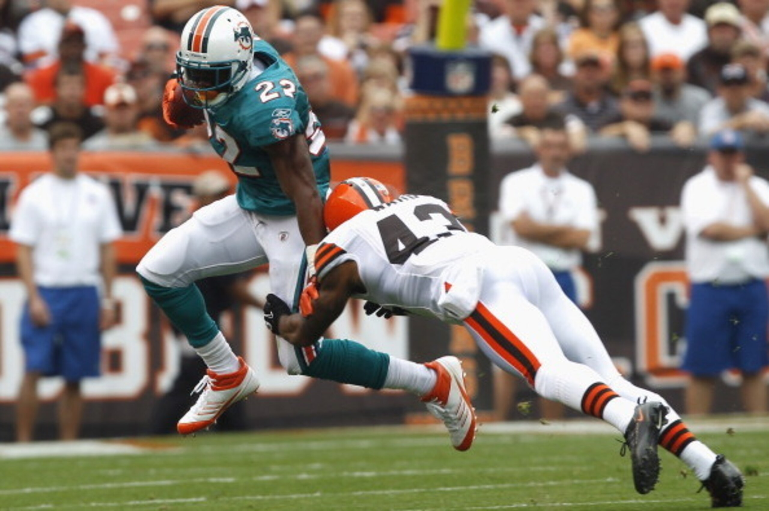 CLEVELAND, OH - SEPTEMBER 25:  Running back Reggie Bush #22 of the Miami Dolphins runs by defensive back T.J. Ward #43 of the Cleveland Browns at Cleveland Browns Stadium on September 25, 2011 in Cleveland, Ohio.  (Photo by Matt Sullivan/Getty Images)