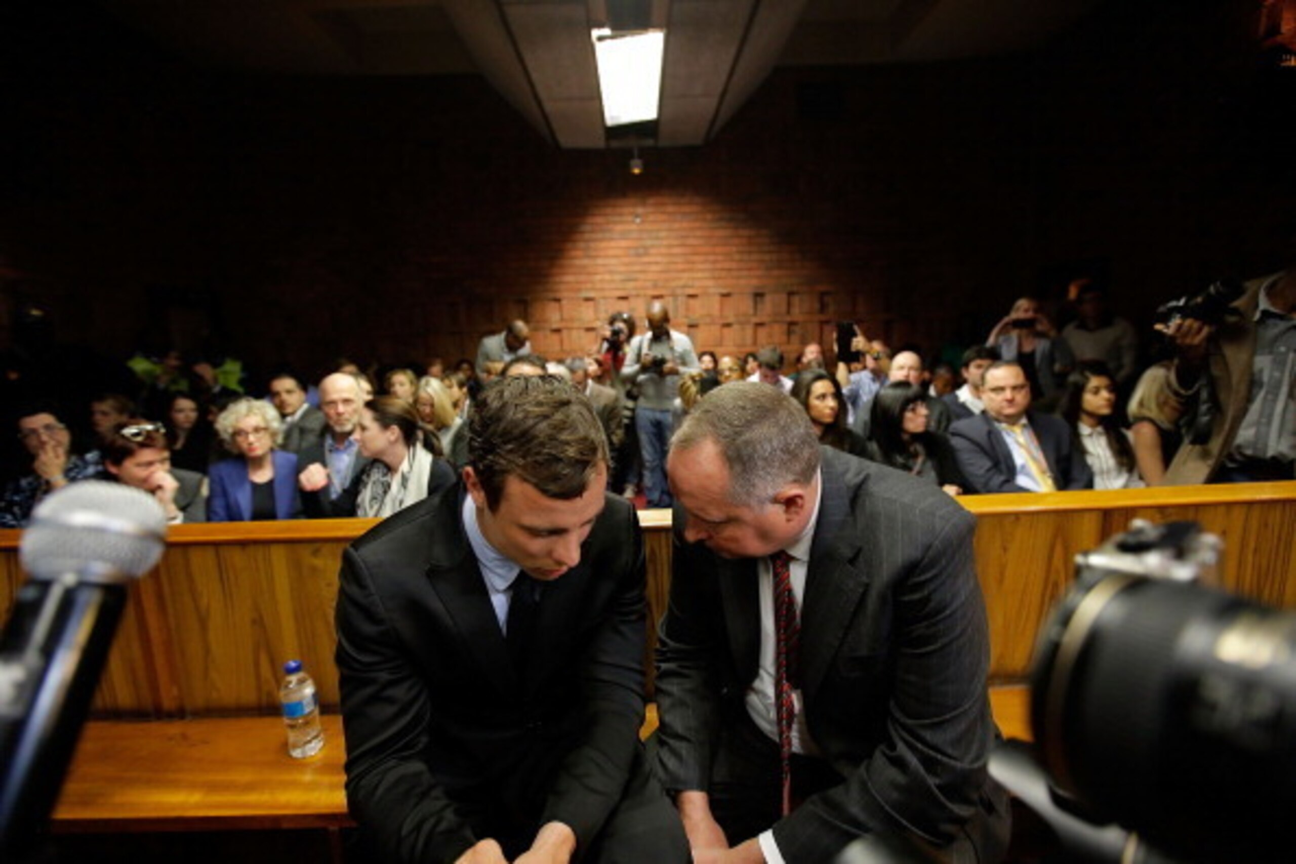 PRETORIA, SOUTH AFRICA - AUGUST 19:  South African athlete Oscar Pistorius (L) speaks with his lawyer Kenny Oldwage in Pretoria Magistrates Court prior to an indictment hearing on August 19, 2013 in Pretoria, South Africa. Pistorius, 26 is accused of murd