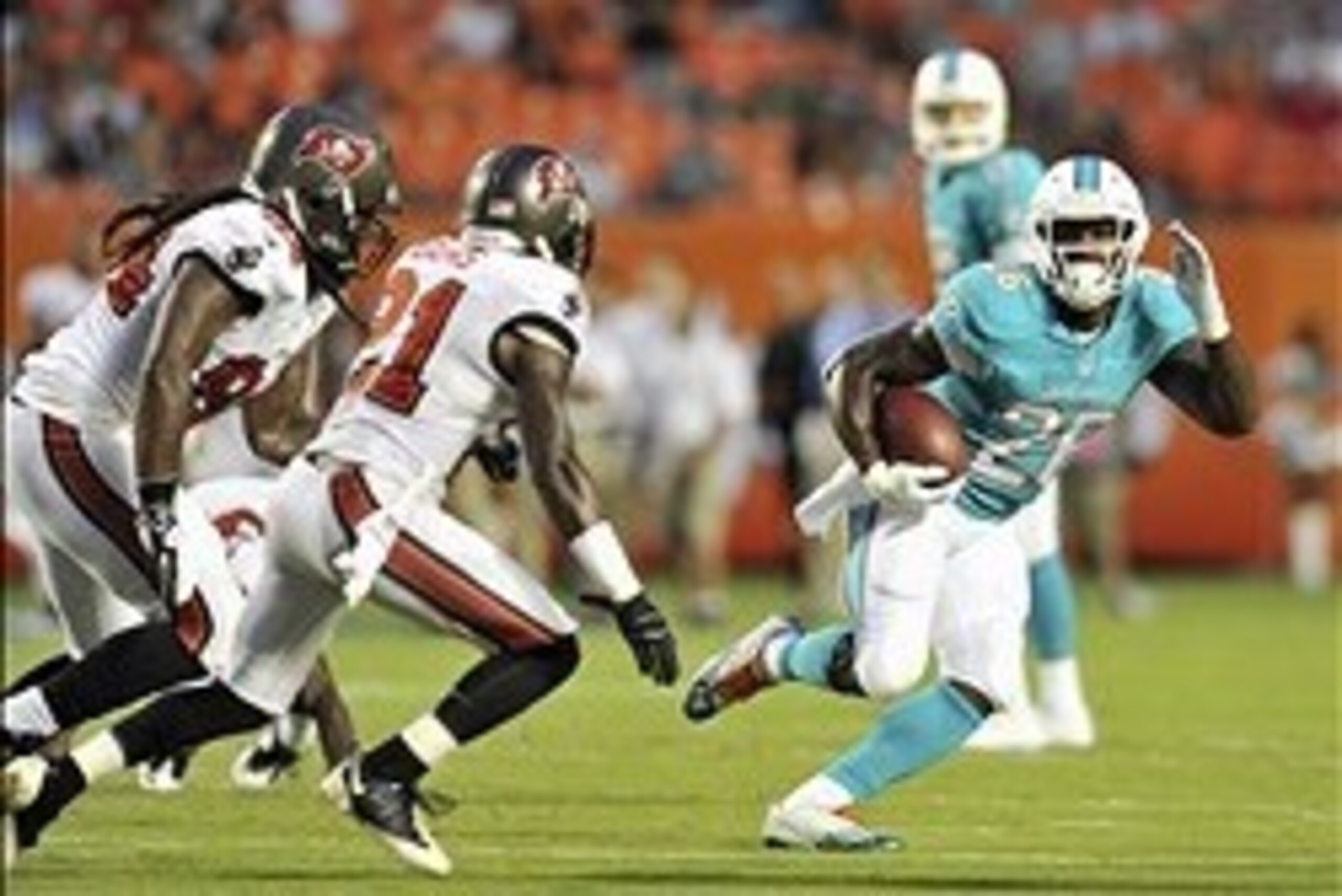 Aug 24, 2013; Miami Gardens, FL, USA; Miami Dolphins running back Lamar Miller (26) is tackled by Tampa Bay Buccaneers cornerback Michael Adams (21) during the first quarter at Sun Life Stadium. Mandatory Credit: Steve Mitchell-USA TODAY Sports