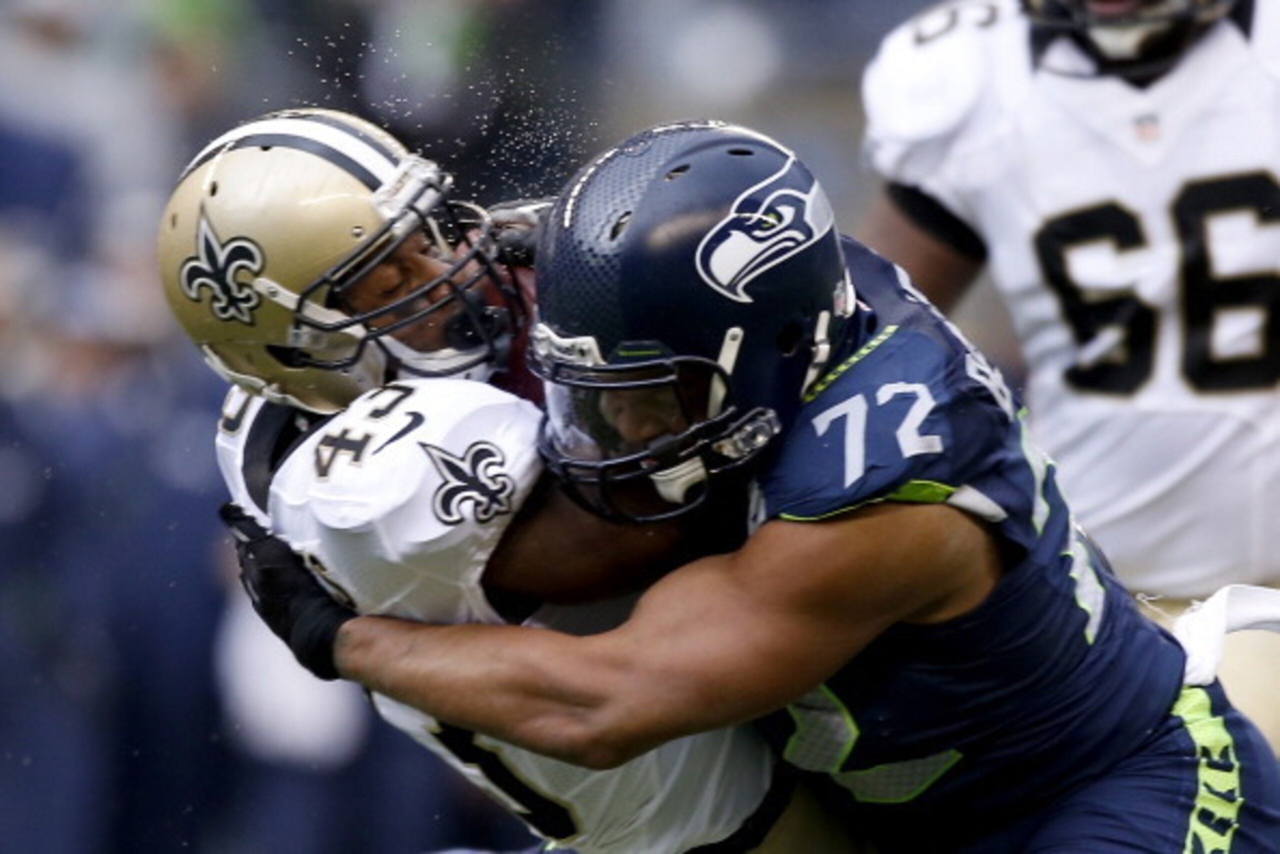 SEATTLE, WA - JANUARY 11:  Running back Darren Sproles #43 of the New Orleans Saints is hit by defensive end Michael Bennett #72 of the Seattle Seahawks in the first half during the NFC Divisional Playoff Game at CenturyLink Field on January 11, 2014 in S