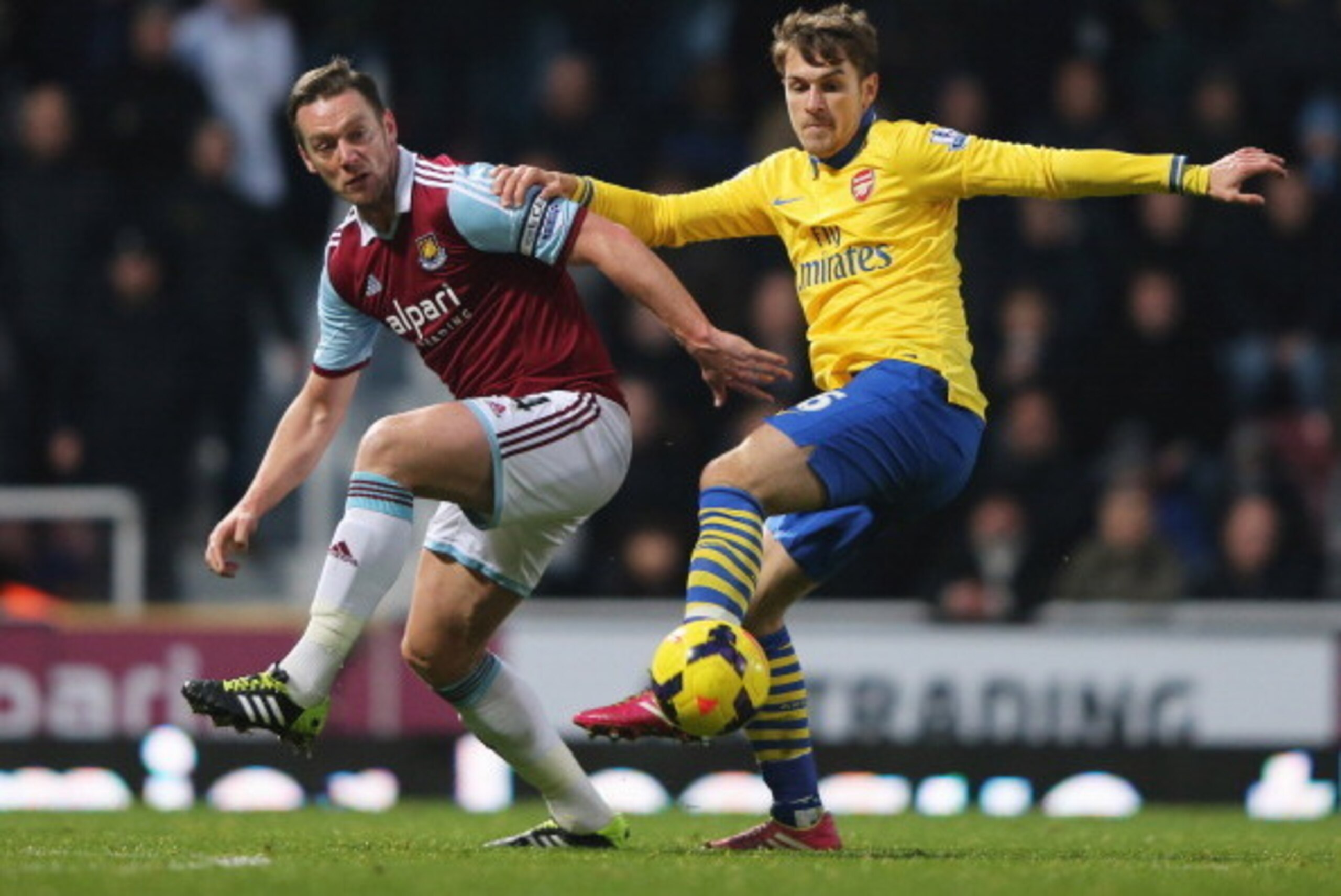 LONDON, ENGLAND - DECEMBER 26:  Aaron Ramsey of Arsenal holds off Kevin Nolan of West Ham United during the Barclays Premier League match between West Ham United and Arsenal at Boleyn Ground on December 26, 2013 in London, England.  (Photo by Ian Walton/G