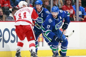 VANCOUVER, BC - OCTOBER 30:  Henrik Sedin #33 of the Vancouver Canucks checks Daniel Alfredsson #11 of the Detroit Red Wings as Ryan Kesler #17 of the Vancouver Canucks skates by during their NHL game at Rogers Arena on October 30, 2013 in Vancouver, Brit