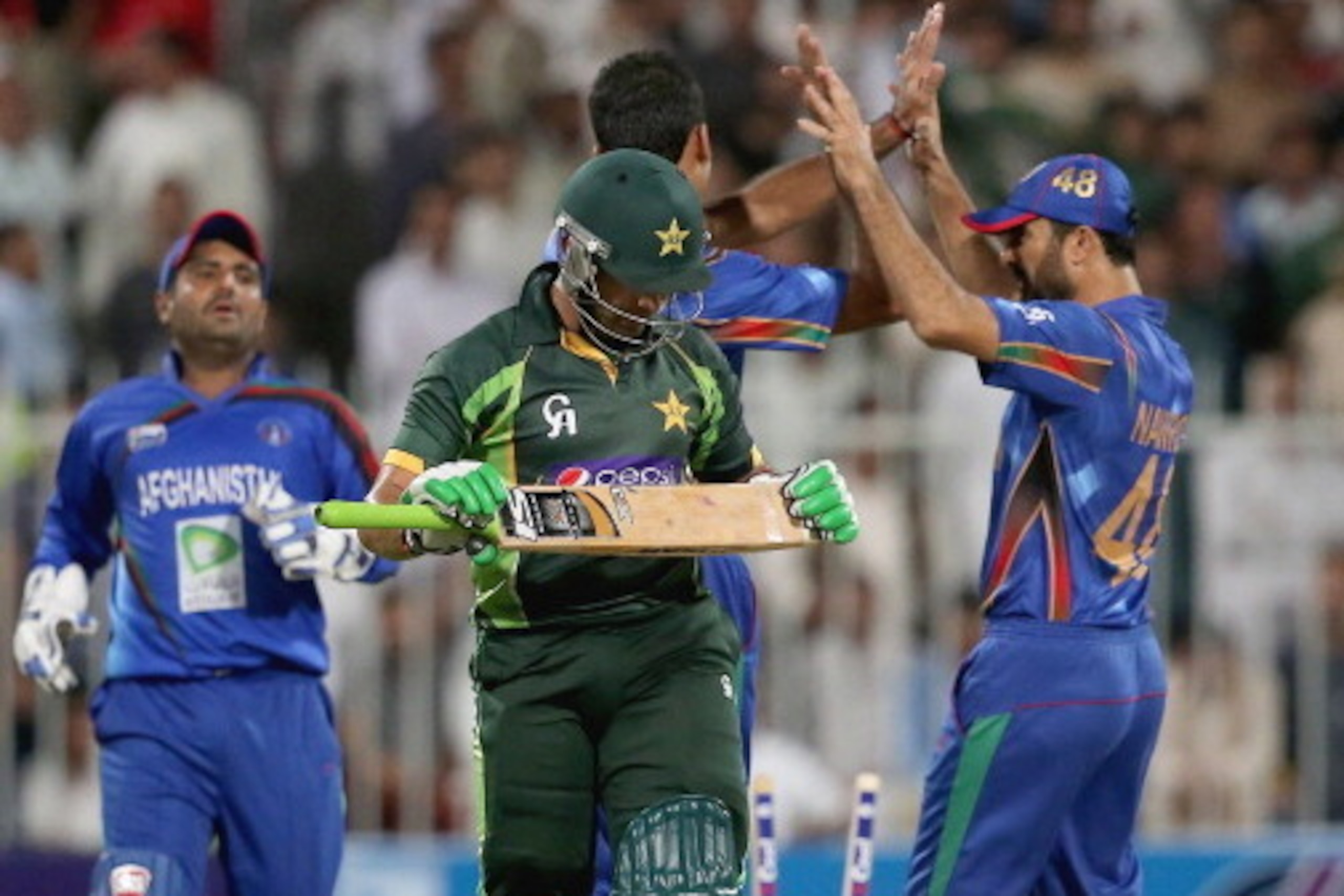 SHARJAH, UNITED ARAB EMIRATES - DECEMBER 08: Afghanistan players celebrate after dismissing Umar Akmal of Pakistan  during the Twenty20 match between Afghanistan and Pakistan at the Sharjah Cricket Stadium on December 8, 2013 in Sharjah, United Arab Emira
