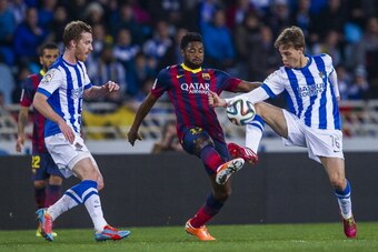 SAN SEBASTIAN, SPAIN - FEBRUARY 12:  Alex Song (C) of FC Barcelona duels for the ball with Sergio Canales (R) of Real Sociedad during the Copa del Rey Semi-Final first leg match between Real Sociedad and Barcelona at Estadio Anoeta  on February 12, 2014 i