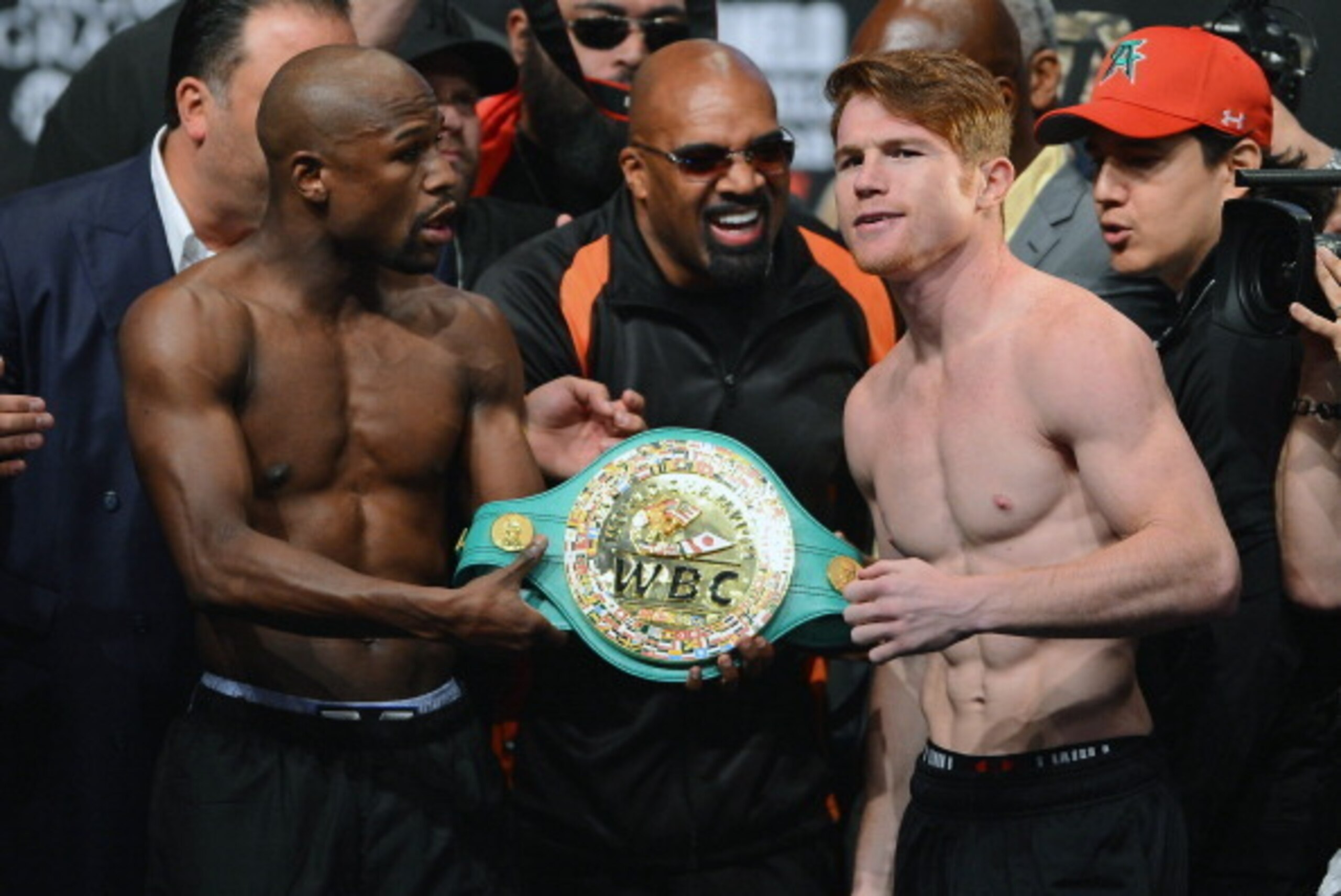 LAS VEGAS, NV - SEPTEMBER 13:   CEO of Mayweather Promotions Leonard Ellerbe (C) looks on as boxer Floyd Mayweather Jr. (L) tries to get boxer Canelo Alvarez (R) to hold a WBC belt as they pose during the official weigh-in for their bout at the MGM Grand 