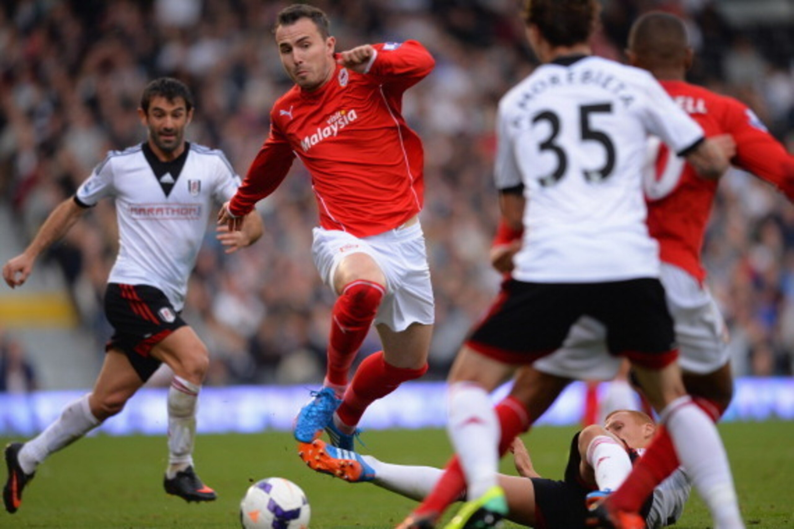 LONDON, ENGLAND - SEPTEMBER 28:  Jordan Mutch of Cardiff jumps a tackle by Steve Sidwell of Fulham during the Barclays Premier League match between Fulham and Cardiff City at Craven Cottage on September 28, 2013 in London, England.  (Photo by Christopher 