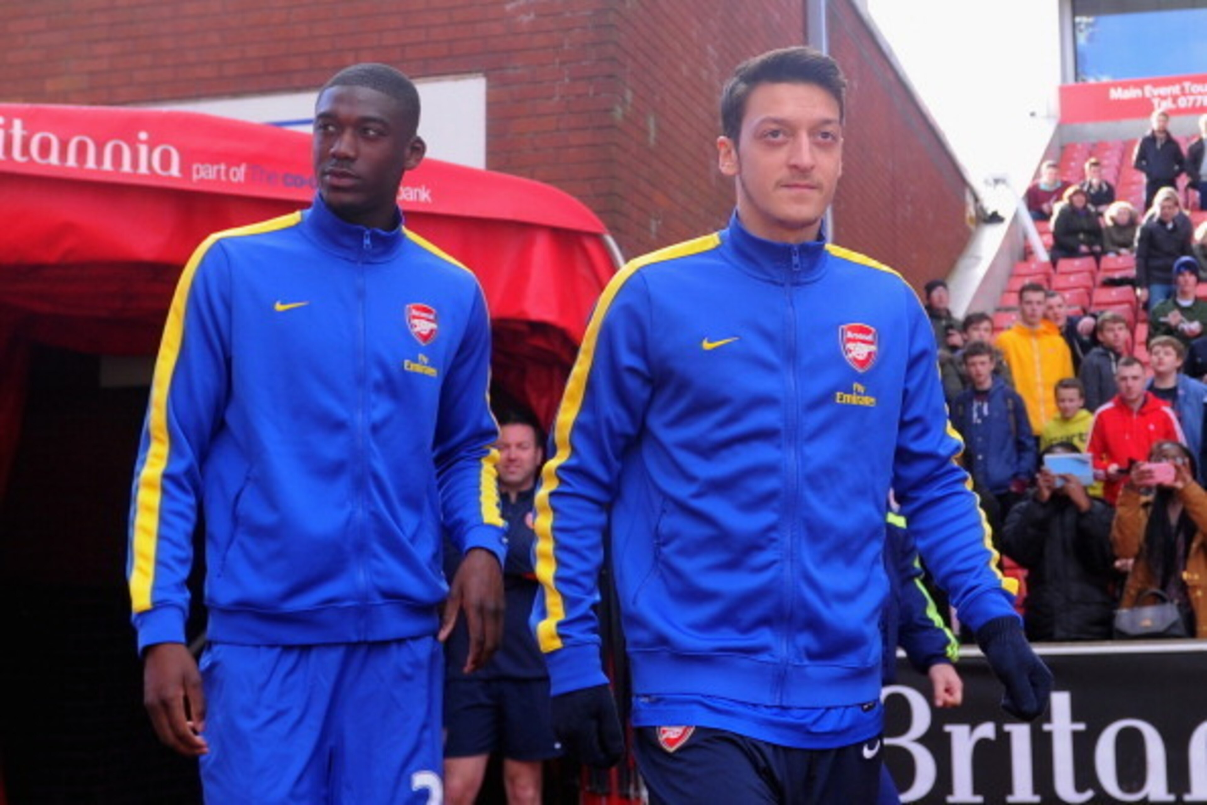STOKE ON TRENT, ENGLAND - MARCH 01:  Mesut Ozil of Arsenal (R) walks out to warm up with team-mate Yaya Sanogo prior to the Barclays Pemier League match between Stoke City and Arsenal at the Britannia Stadium on March 1, 2014 in Stoke on Trent, England.  