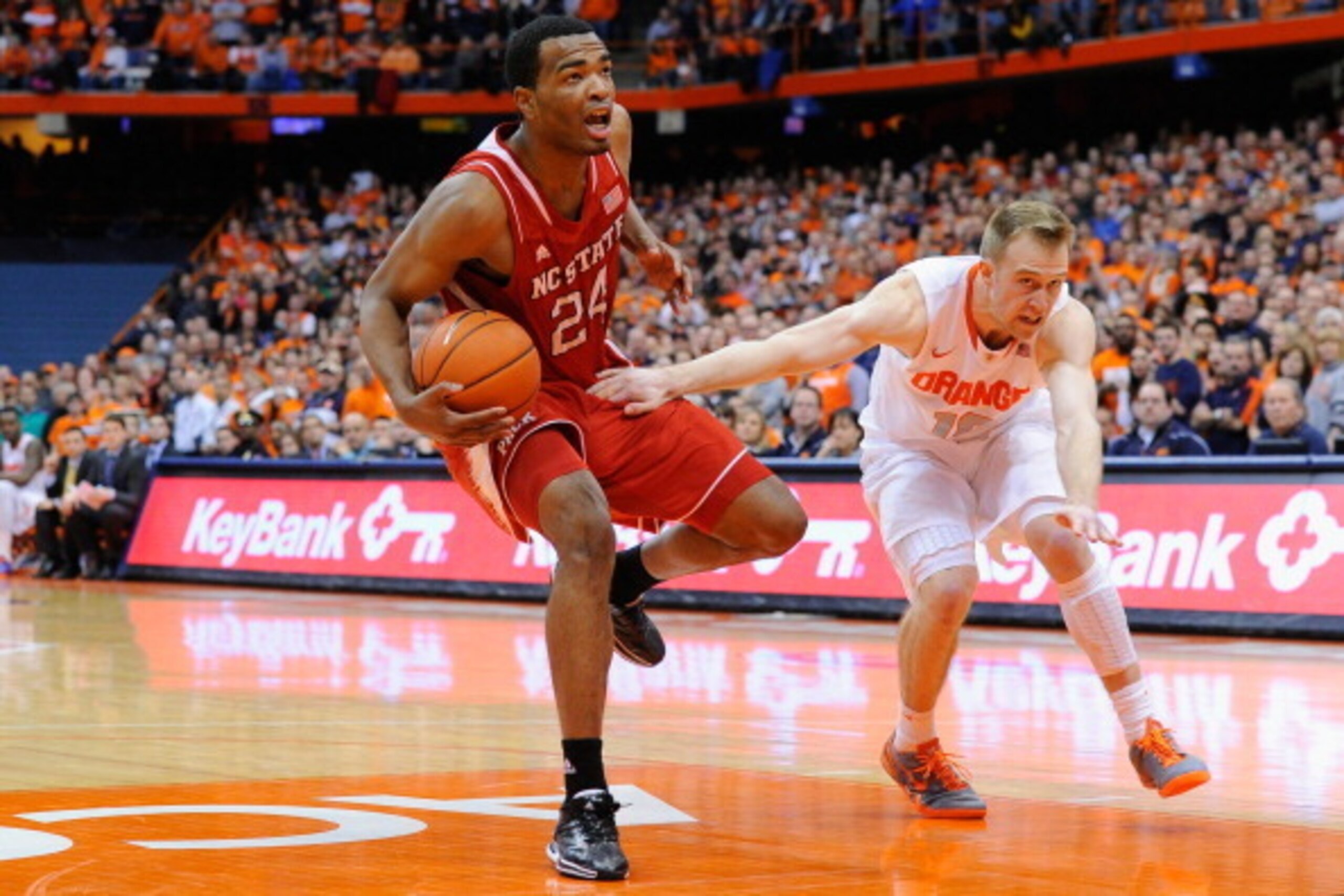 SYRACUSE, NY - FEBRUARY 15:  Trevor Cooney #10 of the Syracuse Orange reaches to foul T.J. Warren #24 of the North Carolina State Wolfpack during the second half at the Carrier Dome on February 15, 2014 in Syracuse, New York.  Syracuse defeated North Caro