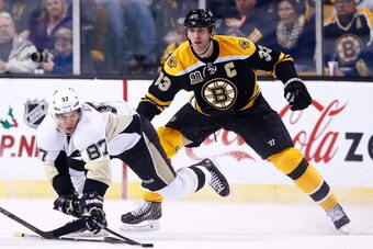 BOSTON, MA - DECEMBER 07: Sidney Crosby #87 of the Pittsburgh Penguins reaches for a puck in front of Zdeno Chara #33 of the Boston Bruins in the third period during the game at TD Garden on December 7, 2013 in Boston, Massachusetts.  (Photo by Jared Wick