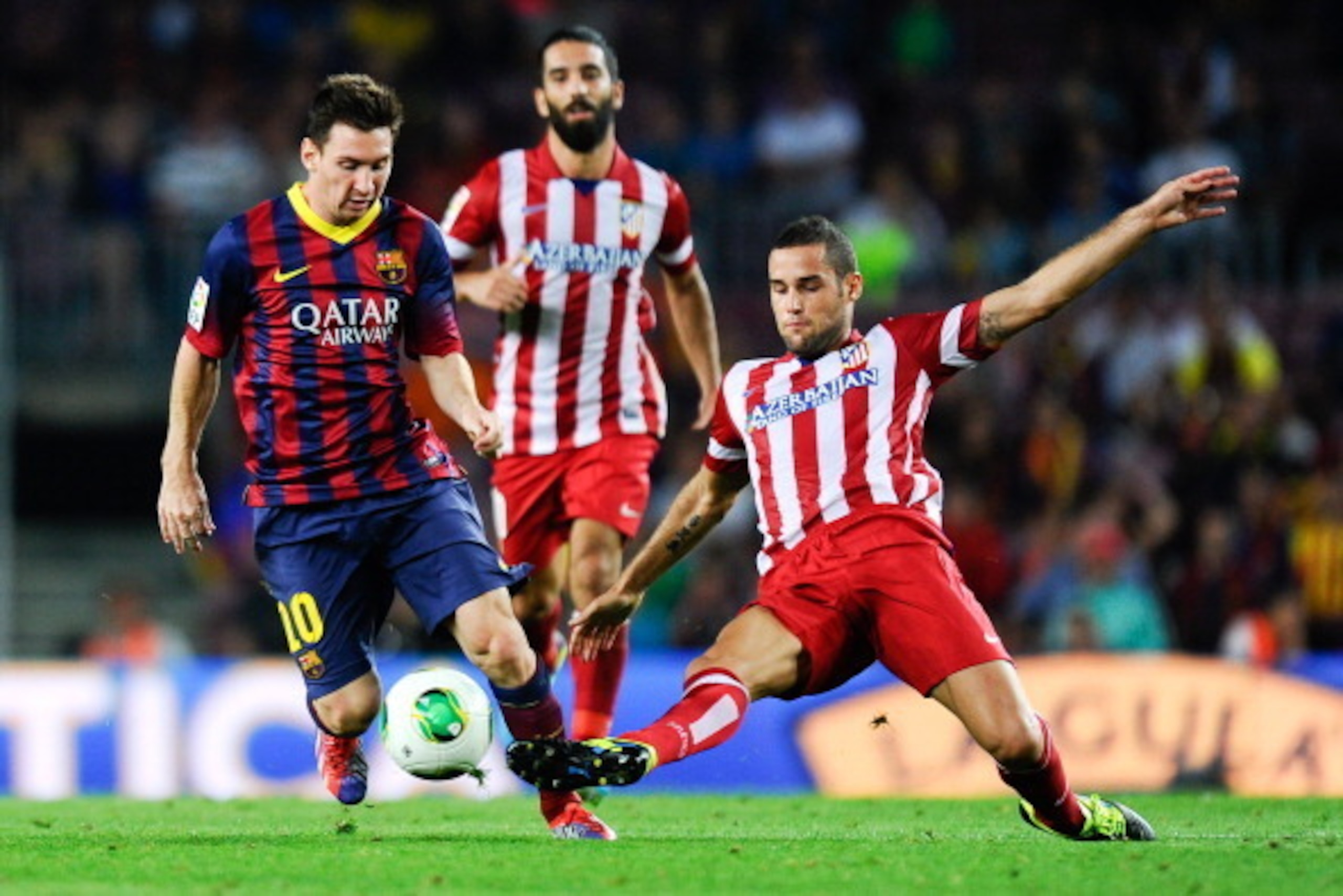 BARCELONA, SPAIN - AUGUST 28:  Lionel Messi (L) of FC Barcelona is challenged by Mario Suarez of Atletico de Madrid during the Spanish Super Cup second leg match between FC Barcelona and Atletico de Madrid at Nou Camp on August 28, 2013 in Barcelona, Spai