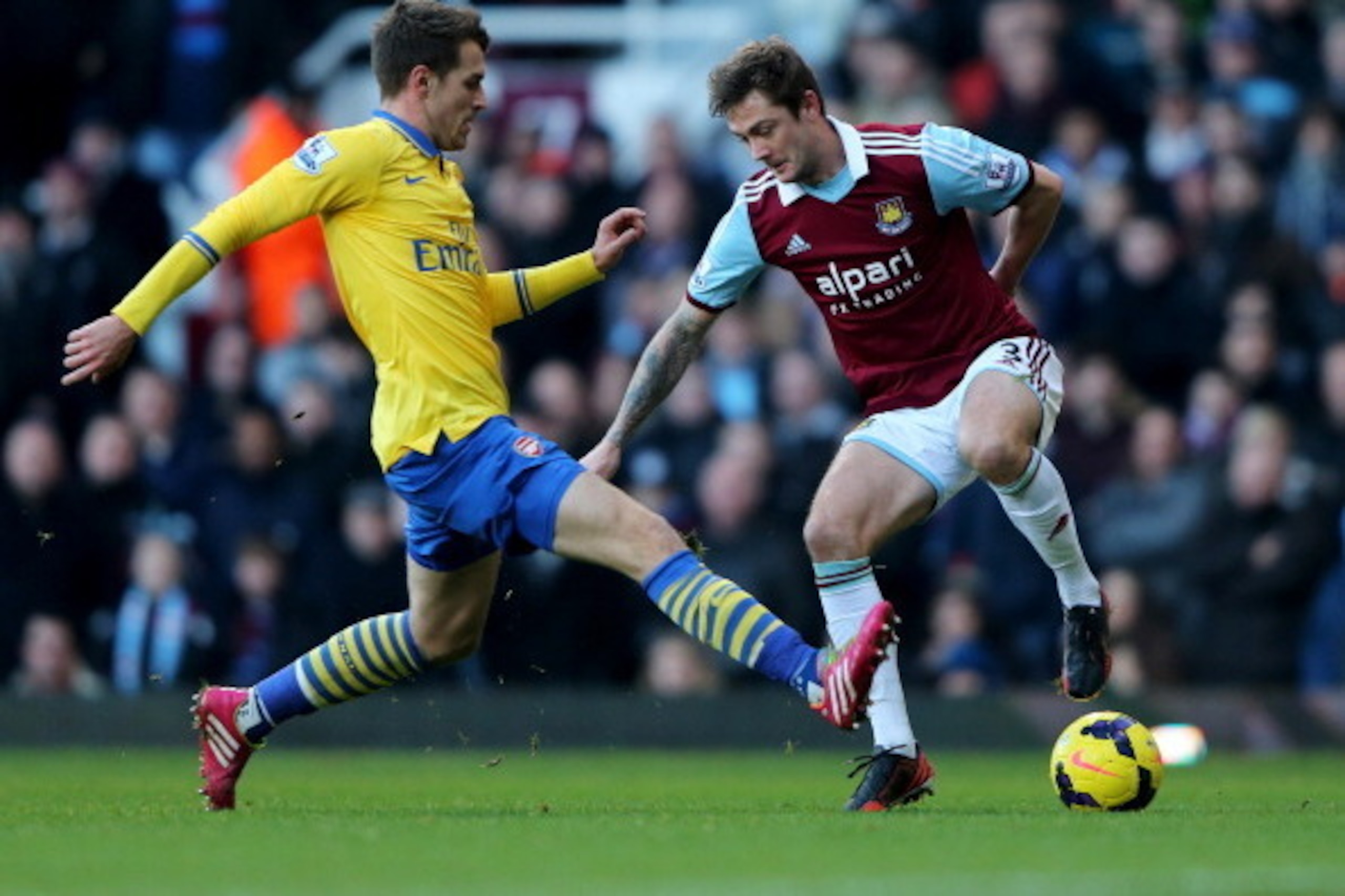LONDON, ENGLAND - DECEMBER 26:  George McCartney of West Ham United is challenged by Aaron Ramsey of Arsenal during the Barclays Premier League match between West Ham United and Arsenal at Boleyn Ground on December 26, 2013 in London, England.  (Photo by 