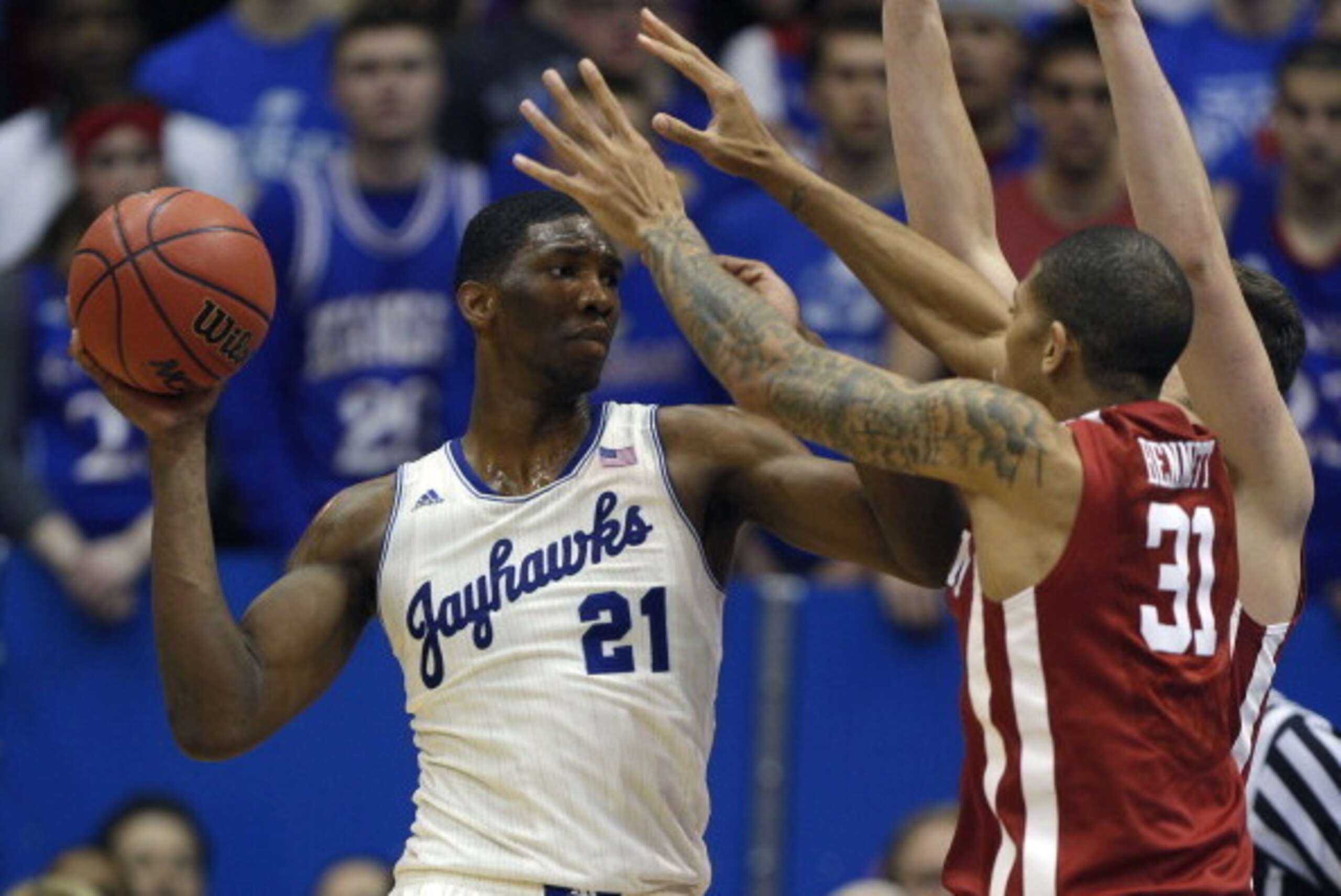 LAWRENCE, KS - FEBRUARY 24:  Joel Embiid #21 of the Kansas Jayhawks looks to pass the ball against D.J. Bennett #31 of the Oklahoma Sooners in the second half at Allen Fieldhouse on February 24, 2014 in Lawrence, Kansas.  Kansas won 83-75. (Photo by Ed Zu