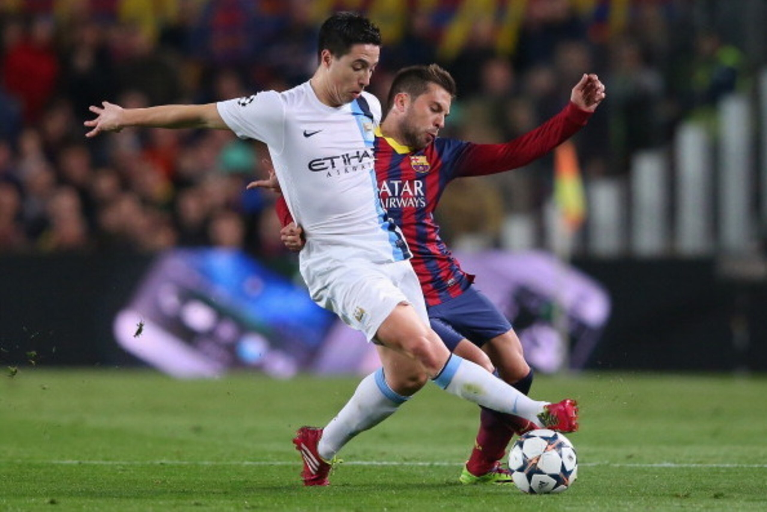 BARCELONA, SPAIN - MARCH 12:  Samir Nasri of Manchester City holds off a challenge from Jordi Alba of FC Barcelona during the UEFA Champions League Round of 16 match between FC Barcelona and Manchester City at Camp Nou on March 12, 2014 in Barcelona, Spai