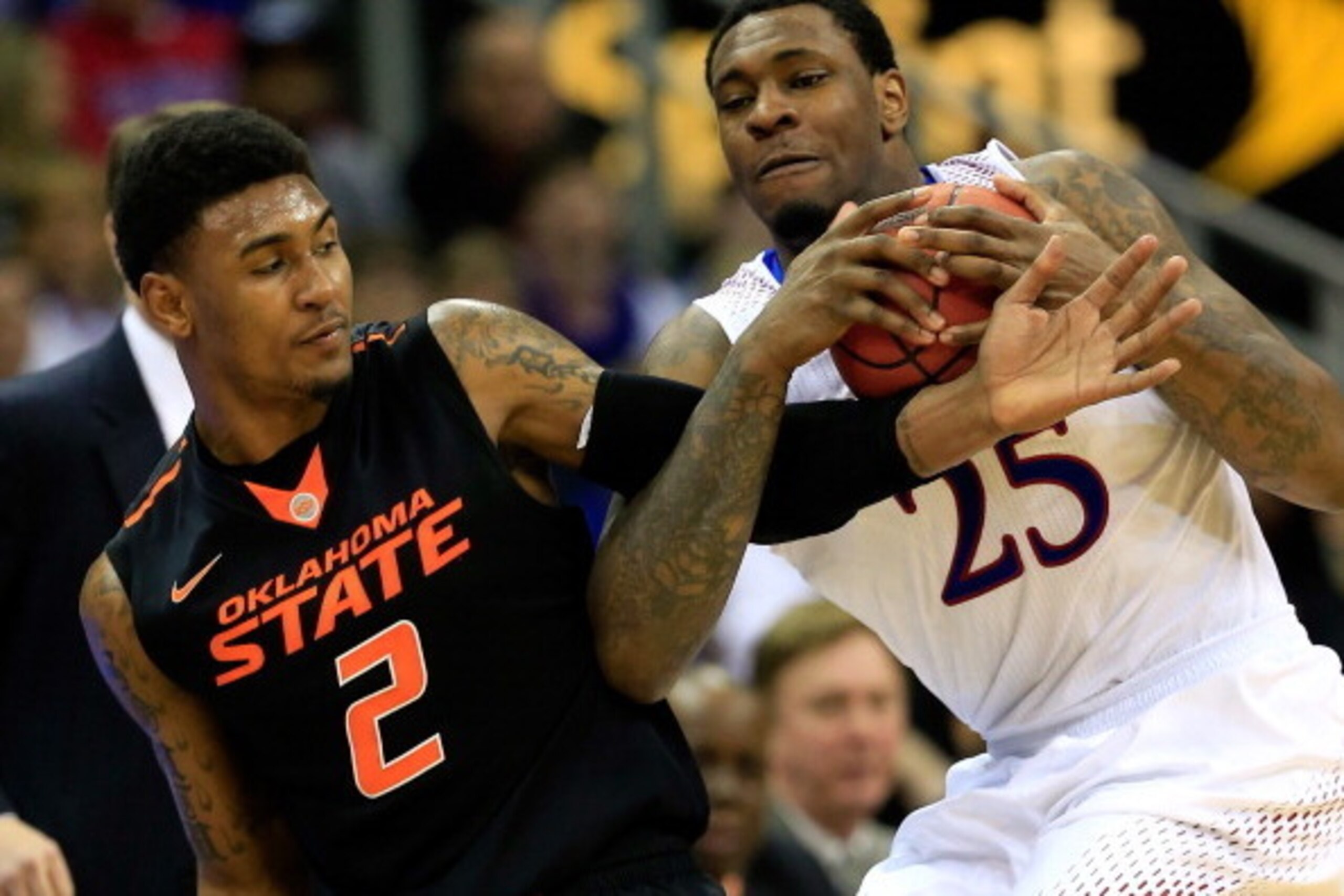 KANSAS CITY, MO - MARCH 13:  Tarik Black #25 of the Kansas Jayhawks and Le'Bryan Nash #2 of the Oklahoma State Cowboys compete for a loose ball during the Big 12 Basketball Tournament quarterfinal game at Sprint Center on March 13, 2014 in Kansas City, Mi