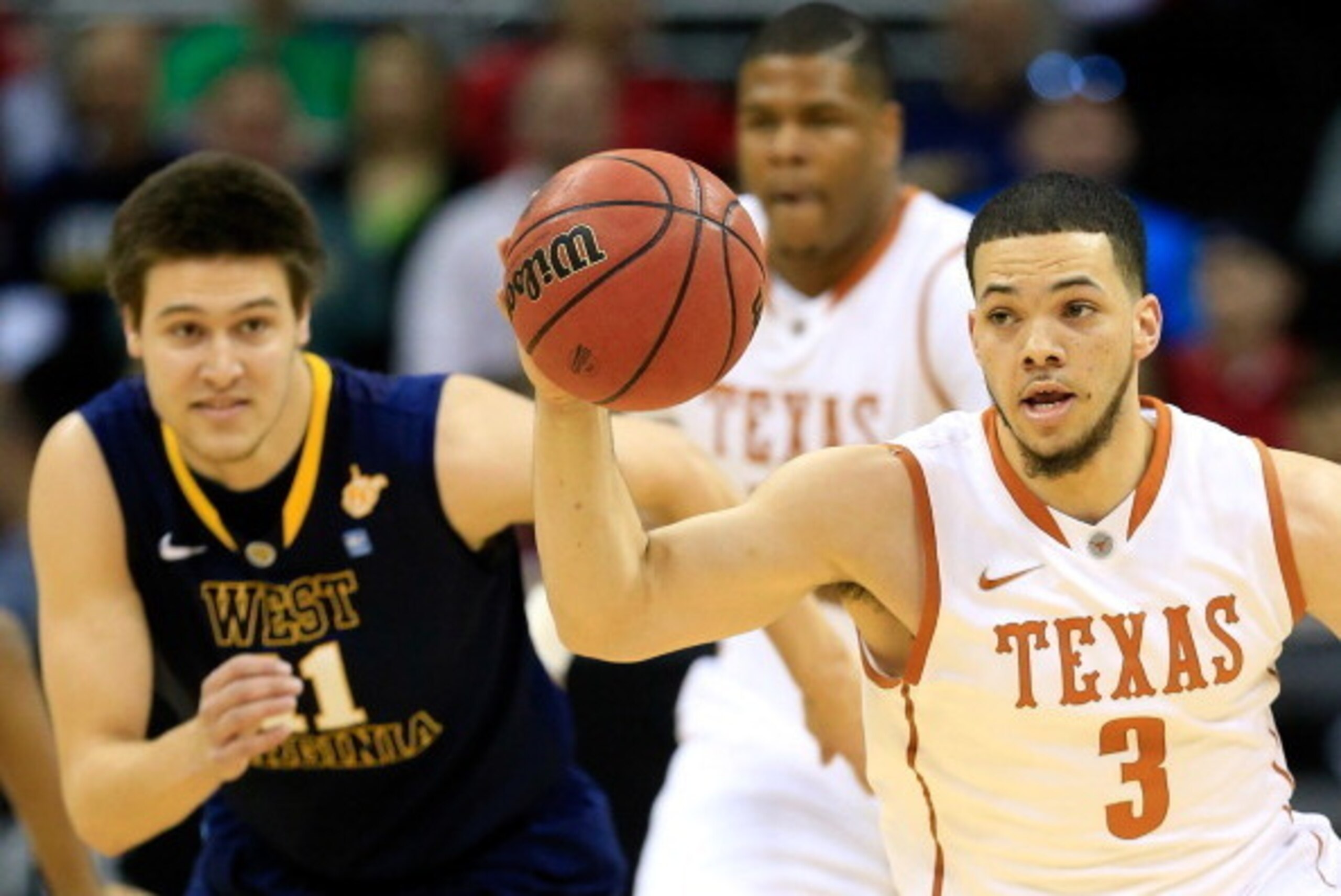 KANSAS CITY, MO - MARCH 13:  Javan Felix #3 of the Texas Longhorns controls the ball as Nathan Adrian #11 of the West Virginia Mountaineers chases during the Big 12 Basketball Tournament quarterfinal game at Sprint Center on March 13, 2014 in Kansas City,