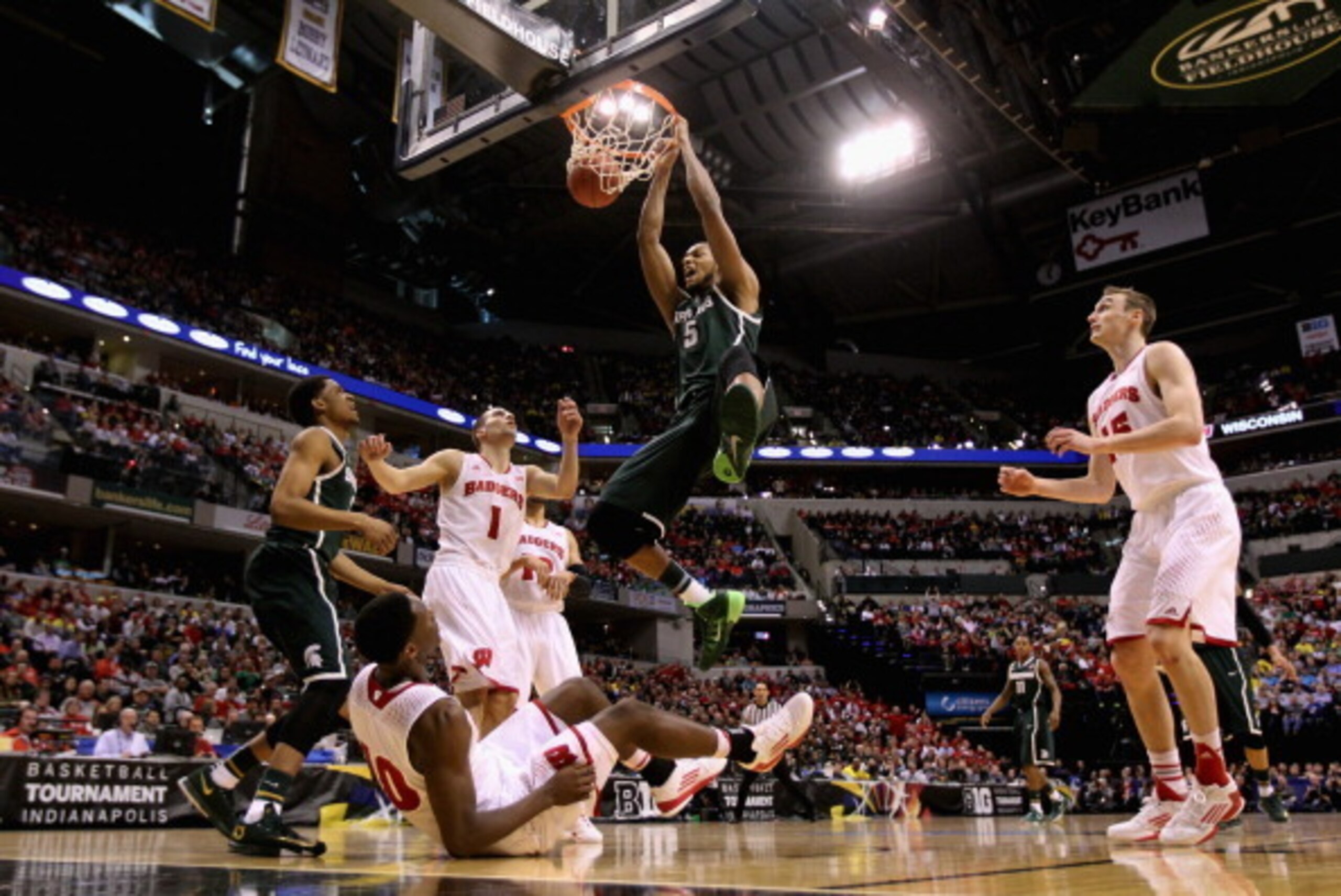 INDIANAPOLIS, IN - MARCH 15:  Adreian Payne #5 of the Michigan State Spartans dunks the ball over Nigel Hayes #10 of the Wisconsin Badgers who falls to the floor during the first half of the Big Ten Basketball Tournament Semifinal game at Bankers Life Fie