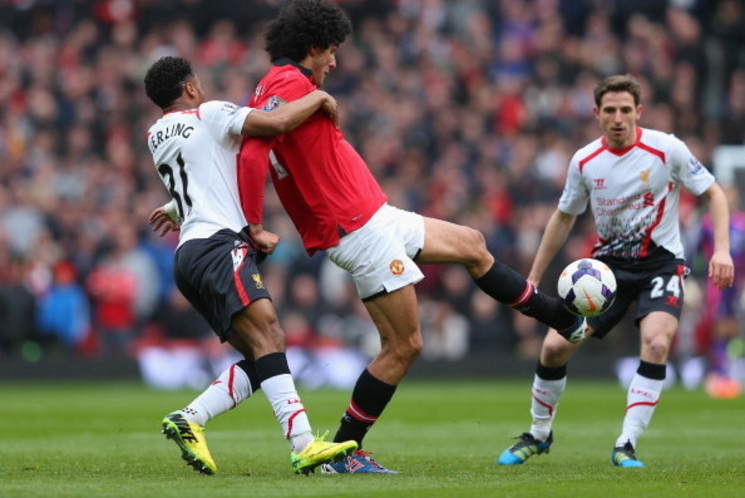 MANCHESTER, ENGLAND - MARCH 16:  Marouane Fellaini of Manchester United tangles with Raheem Sterling of Liverpool during the Barclays Premier League match between Manchester United and Liverpool at Old Trafford on March 16, 2014 in Manchester, England.  (