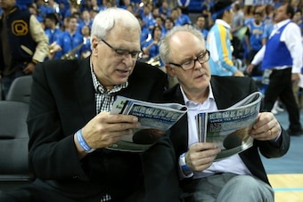 LOS ANGELES, CA - JANUARY 09:  NBA coaching legend Phil Jackson (L) and actor John Lithgow consult their programs before the game between the Arizona Wildcats and the UCLA Bruins at Pauley Pavilion on January 9, 2014 in Los Angeles, California.  (Photo by