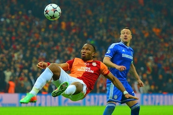 ISTANBUL, TURKEY - FEBRUARY 26:  John Terry of Chelsea looks on as Didier Drogba of Galatasaray clears the ball during the UEFA Champions League Round of 16 first leg match between Galatasaray AS and Chelsea at Ali Sami Yen Arena on February 26, 2014 in I