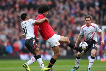 MANCHESTER, ENGLAND - MARCH 16:  Marouane Fellaini of Manchester United tangles with Raheem Sterling of Liverpool during the Barclays Premier League match between Manchester United and Liverpool at Old Trafford on March 16, 2014 in Manchester, England.  (