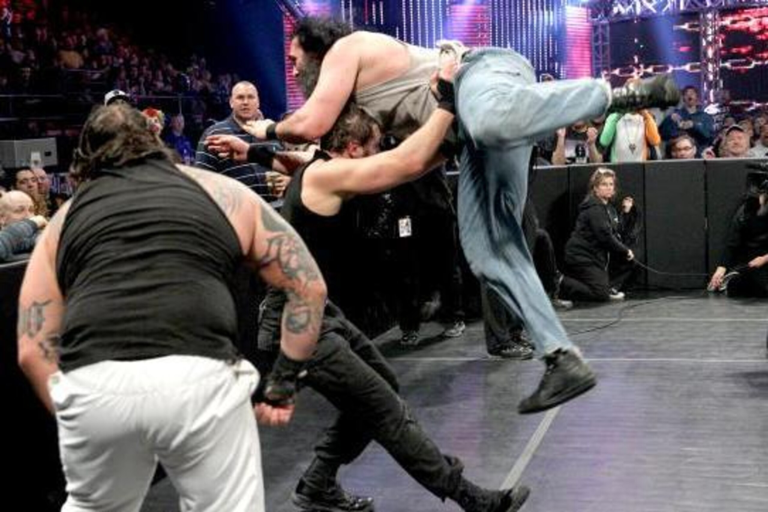 Luke Harper dives out of the ring onto Dean Ambrose.