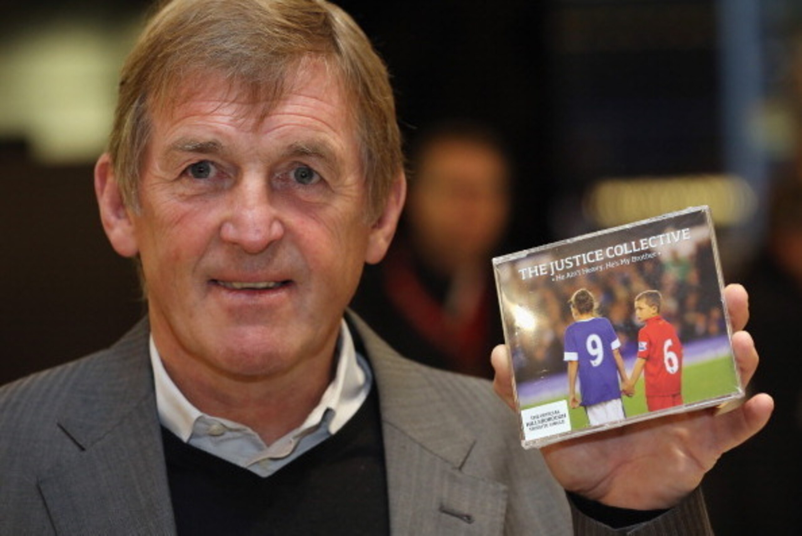 LIVERPOOL, ENGLAND - DECEMBER 17:  Former Liverpool manager Kenny Dalglish poses with the charity single 'He Ain't Heavy, He's My Brother' by The Justice Collective, in aid of the families of victims of the 1989 Hillsborough tragedy on December 17, 2012 i