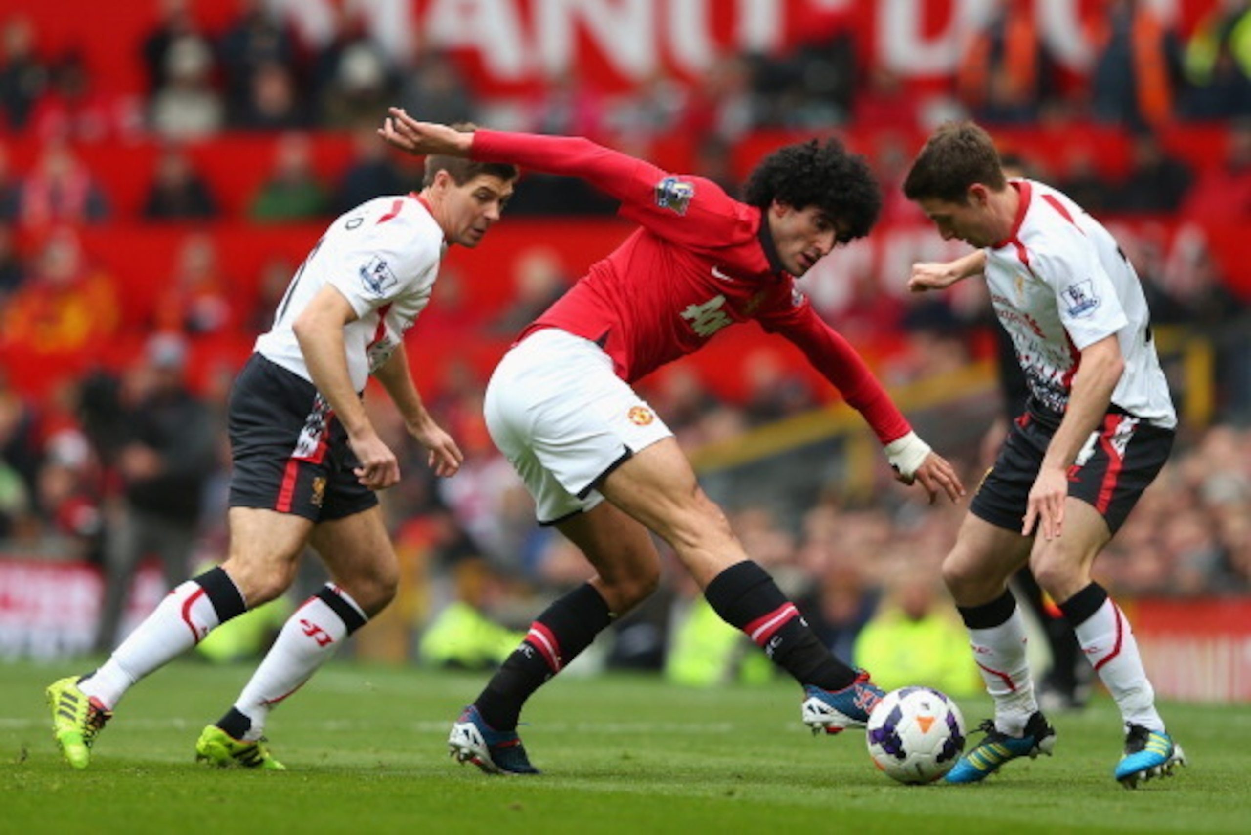 MANCHESTER, ENGLAND - MARCH 16:  Marouane Fellaini of Manchester United competes with Joe Allen (R) and Steven Gerrard of Liverpool during the Barclays Premier League match between Manchester United and Liverpool at Old Trafford on March 16, 2014 in Manch