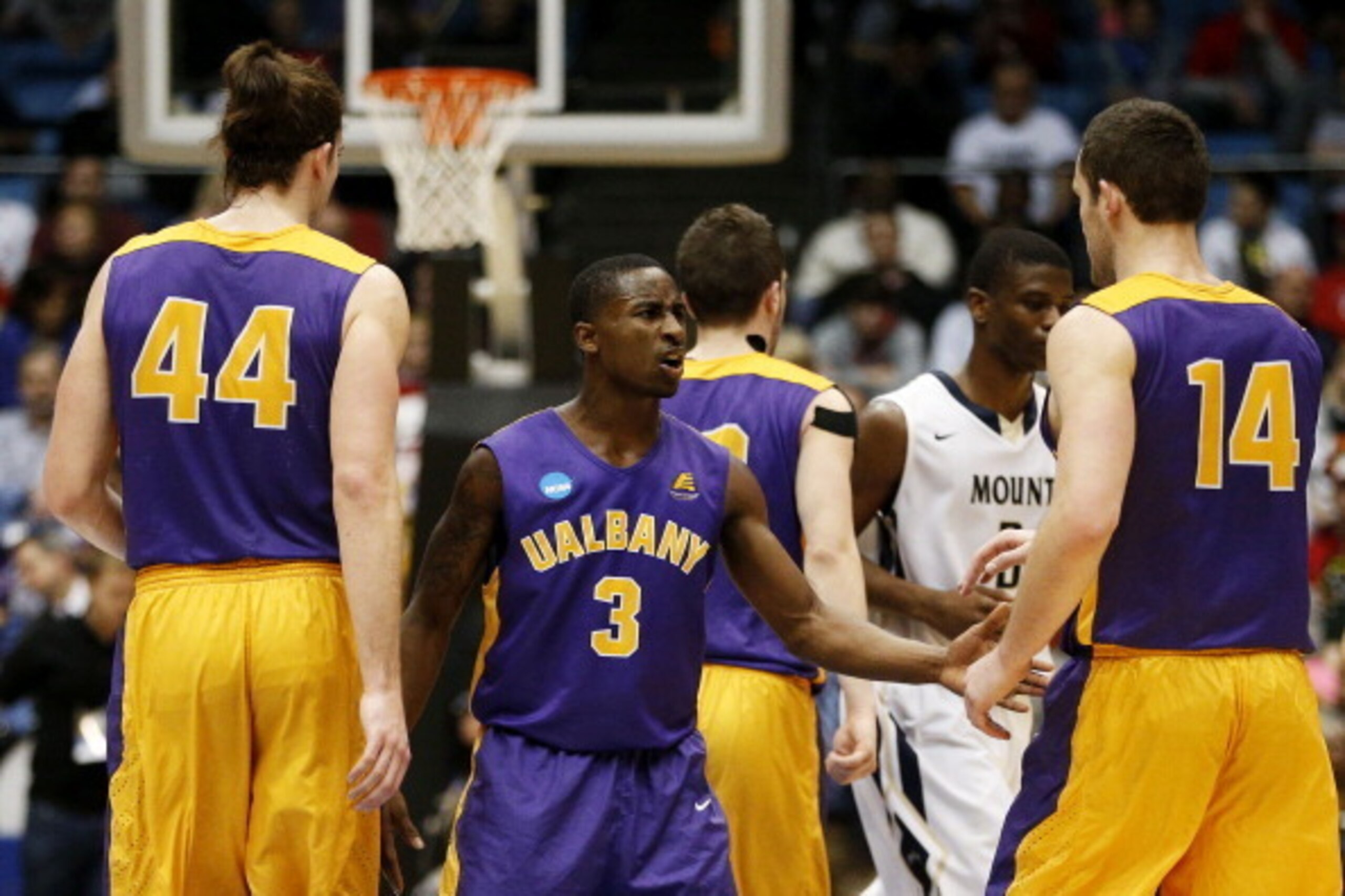 DAYTON, OH - MARCH 18:  DJ Evans #3 celebrates with John Puk #44 and Sam Rowley #14 of the Albany Great Danes during their 71 to 64 win over the Mount St. Mary's Mountaineers during the first round of the 2014 NCAA Men's Basketball Tournament at at Univer
