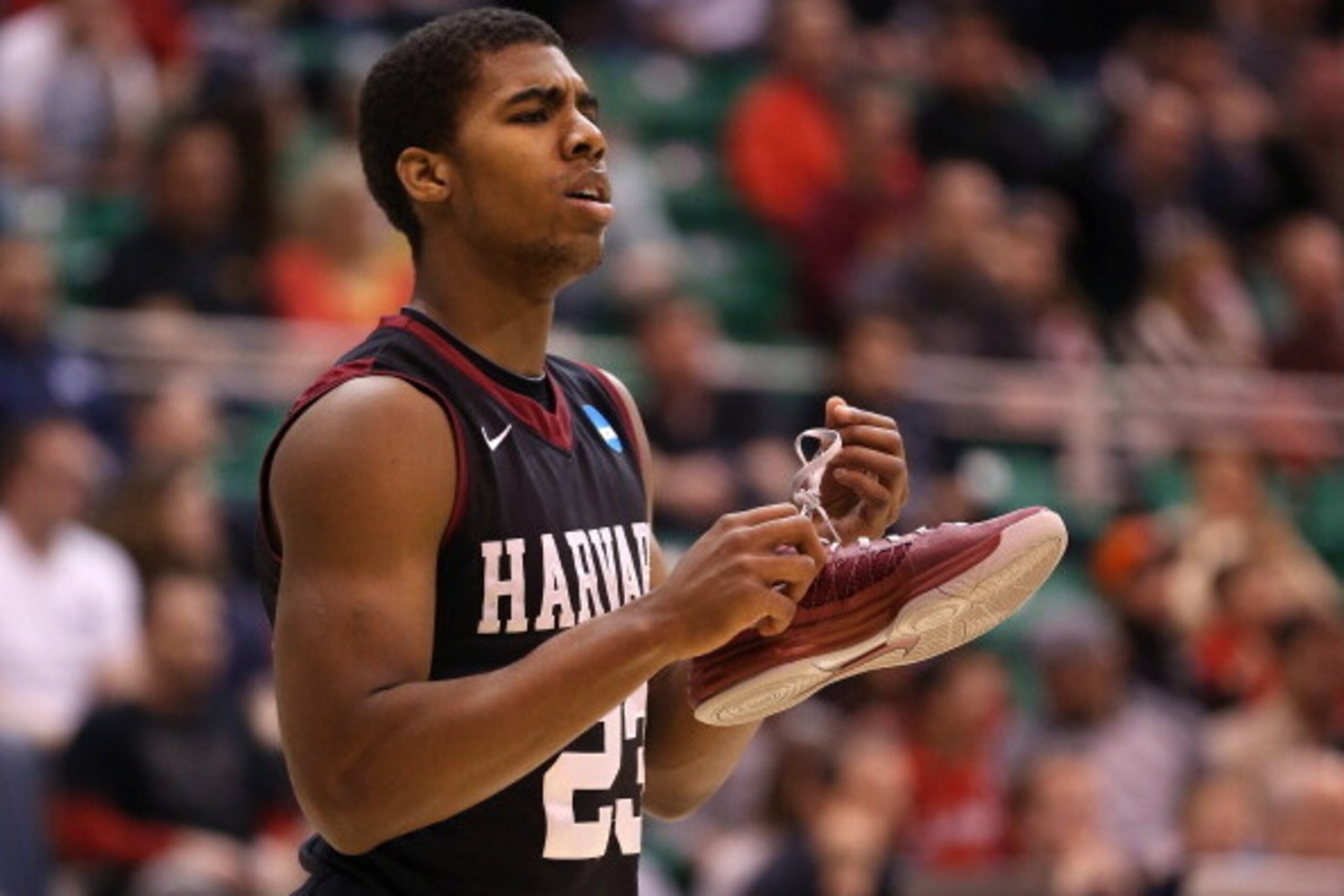 SALT LAKE CITY, UT - MARCH 23:  Wesley Saunders #23 of the Harvard Crimson holds onto his shoe in the first half while taking on the Arizona Wildcats during the third round of the 2013 NCAA Men's Basketball Tournament at EnergySolutions Arena on March 23,