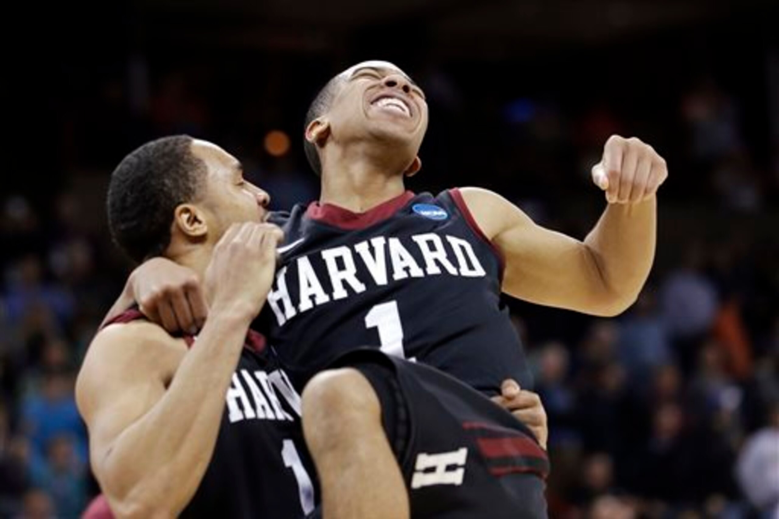 Harvard's Siyani Chambers, right, leaps into the arms of teammate Brandyn Curry after the team beat Cincinnati in the second round of the NCAA college basketball tournament in Spokane, Wash., Thursday, March 20, 2014. Harvard won 61-57. (AP Photo/Elaine T