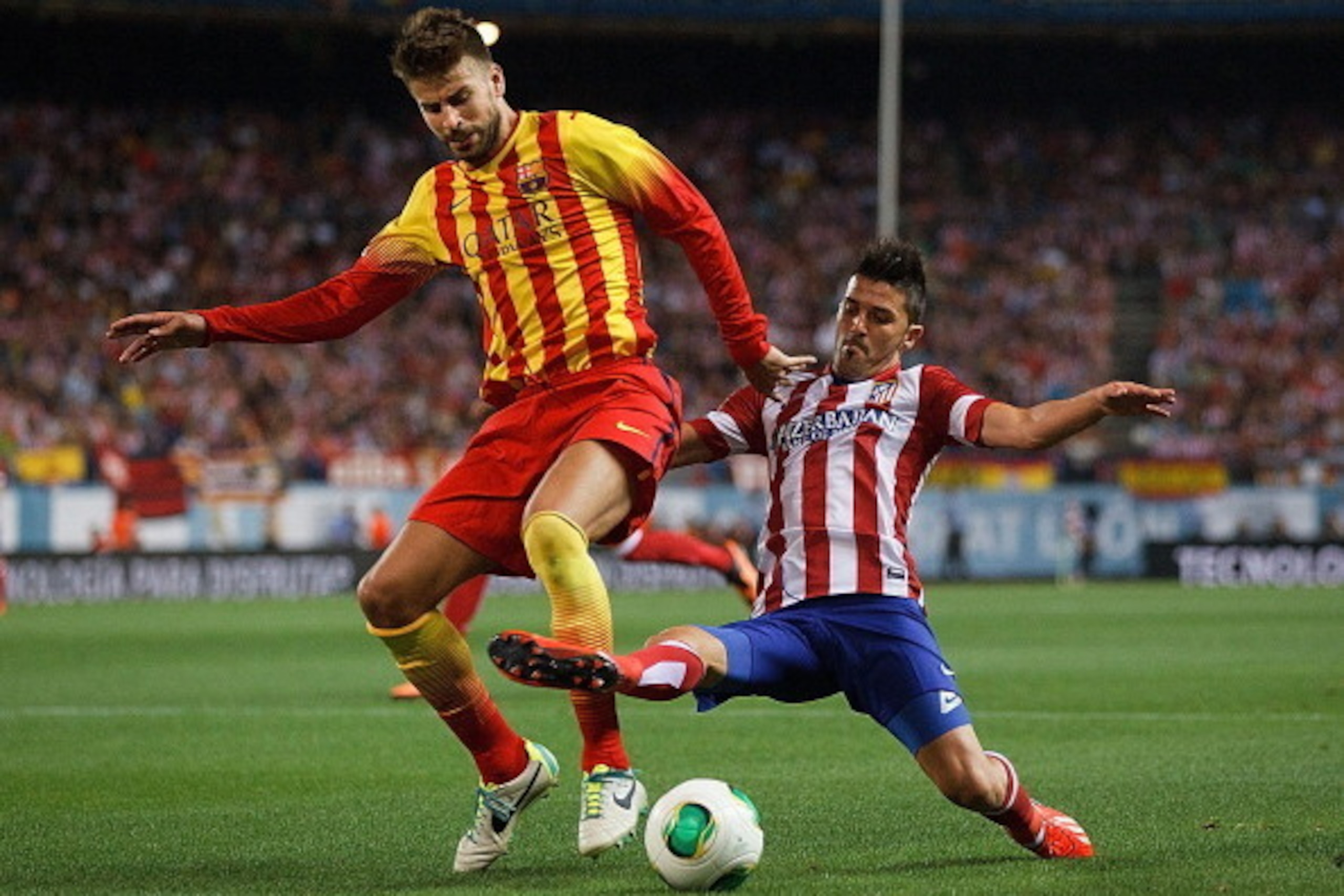 MADRID, SPAIN - AUGUST 21: Gerard Pique (L) of FC Barcelona competes for the ball with David Villa (R) of Atletico de Madrid during the Spanish Super Cup first leg match between Club Atletico de Madrid and FC Barcelona at Vicente Calderon Stadium on Augus