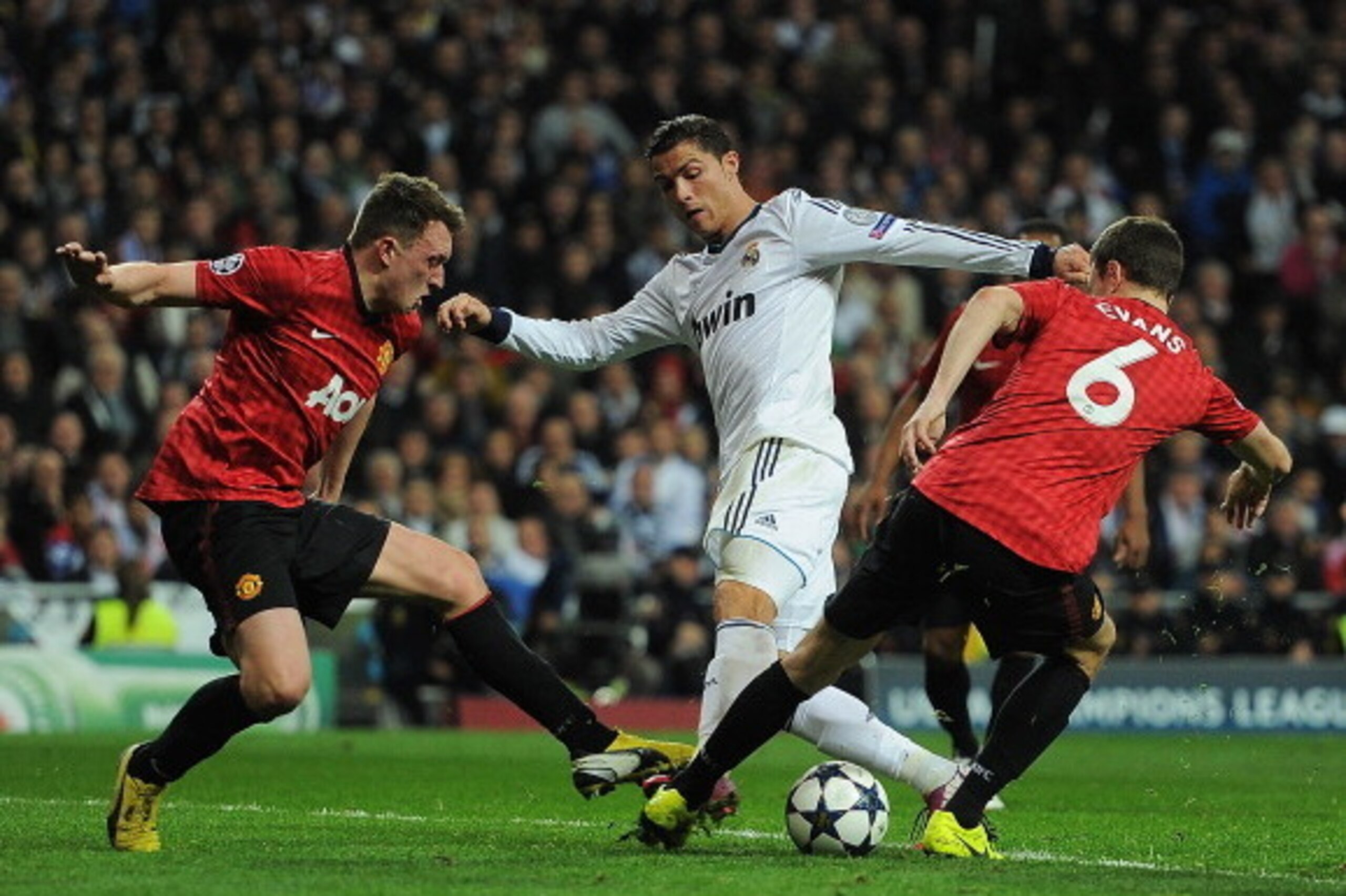 MADRID, SPAIN - FEBRUARY 13:  Cristiano Ronaldo of Real Madrid is put under pressure by Jonny Evans and Phil Jones of Manchester United  during the UEFA Champions League Round of 16 first leg match between Real Madrid and Manchester United at Estadio Sant