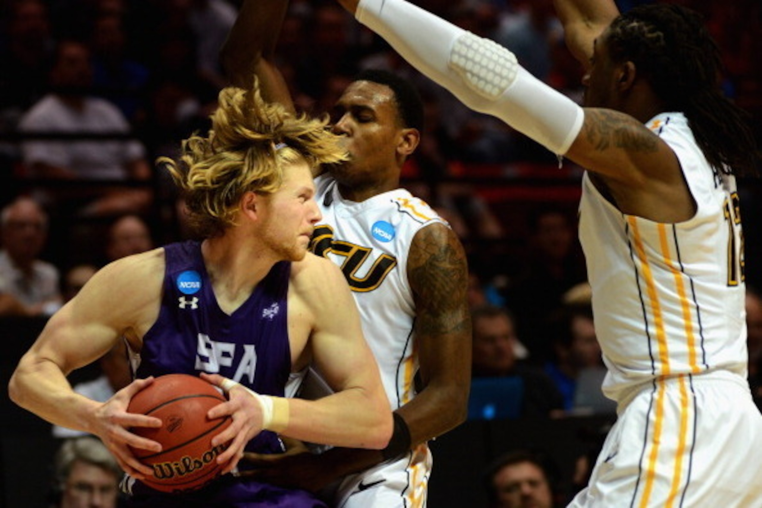 SAN DIEGO, CA - MARCH 21:  Jacob Parker #34 of the Stephen F. Austin Lumberjacks is defended by Treveon Graham #21 and Mo Alie-Cox #12 of the Virginia Commonwealth Rams during the second round of the 2014 NCAA Men's Basketball Tournament at Viejas Arena o